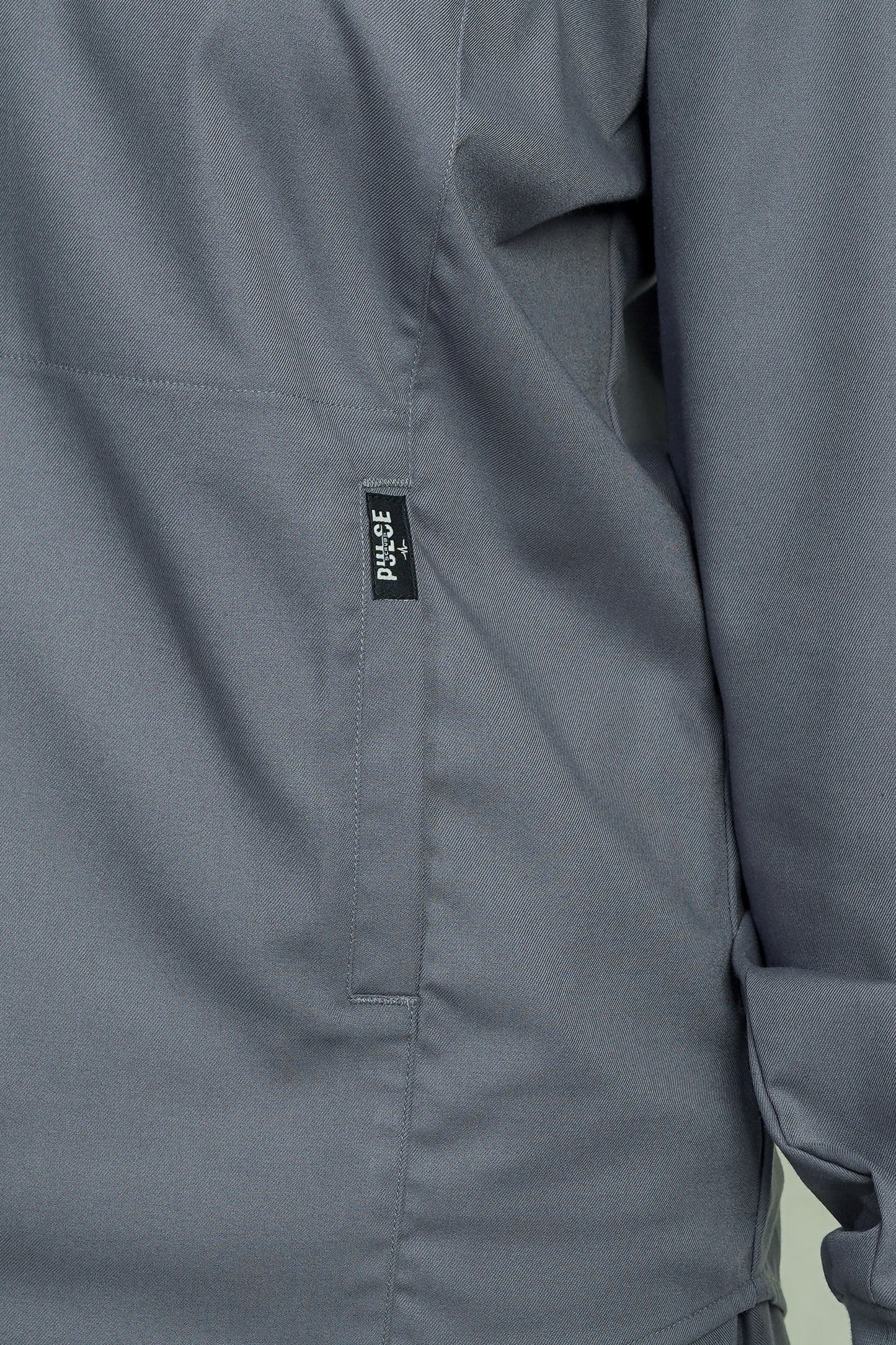 Close-up of a gray jacket with a visible brand label on a light green background