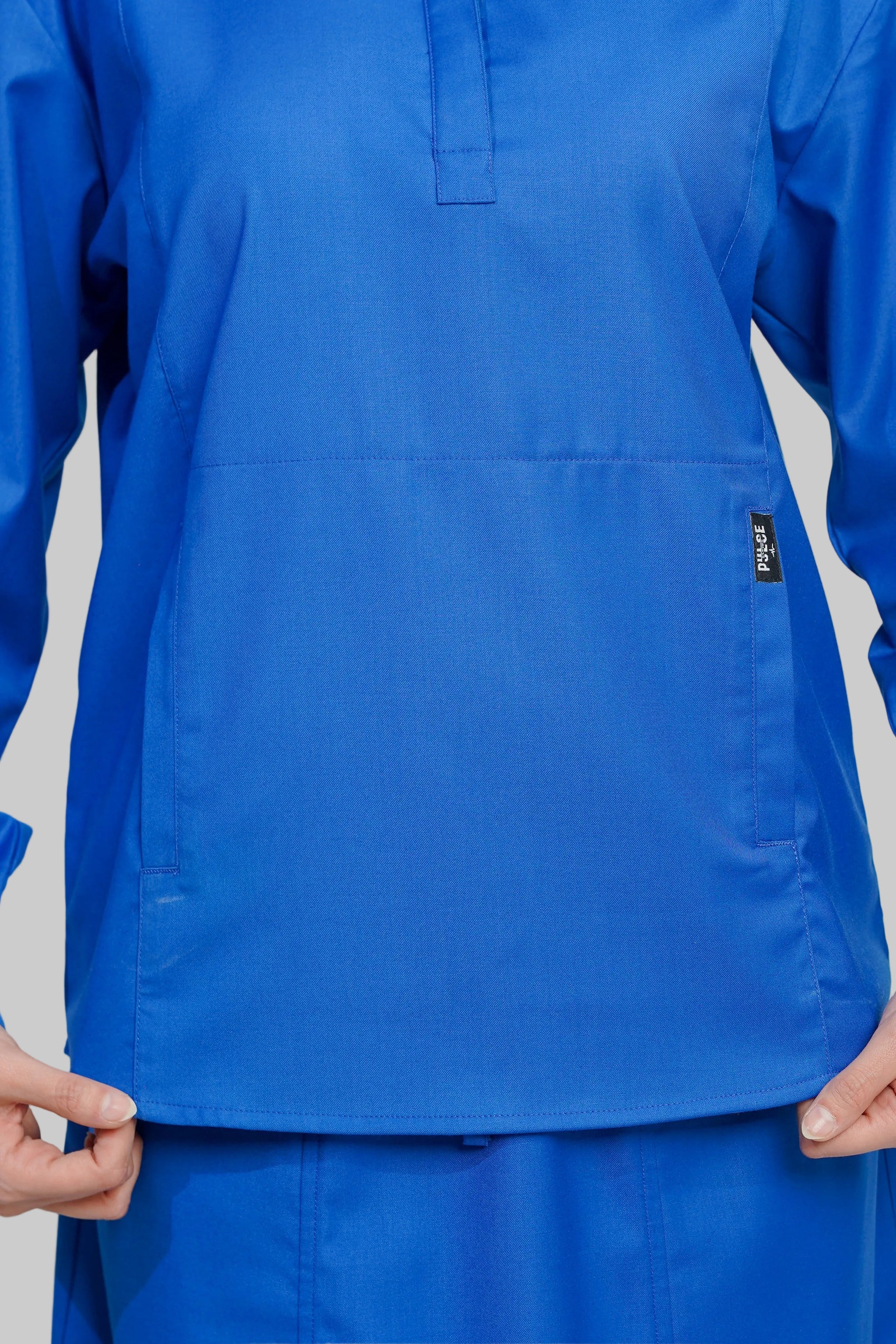 Blue scrub top with a pocket on a gray background