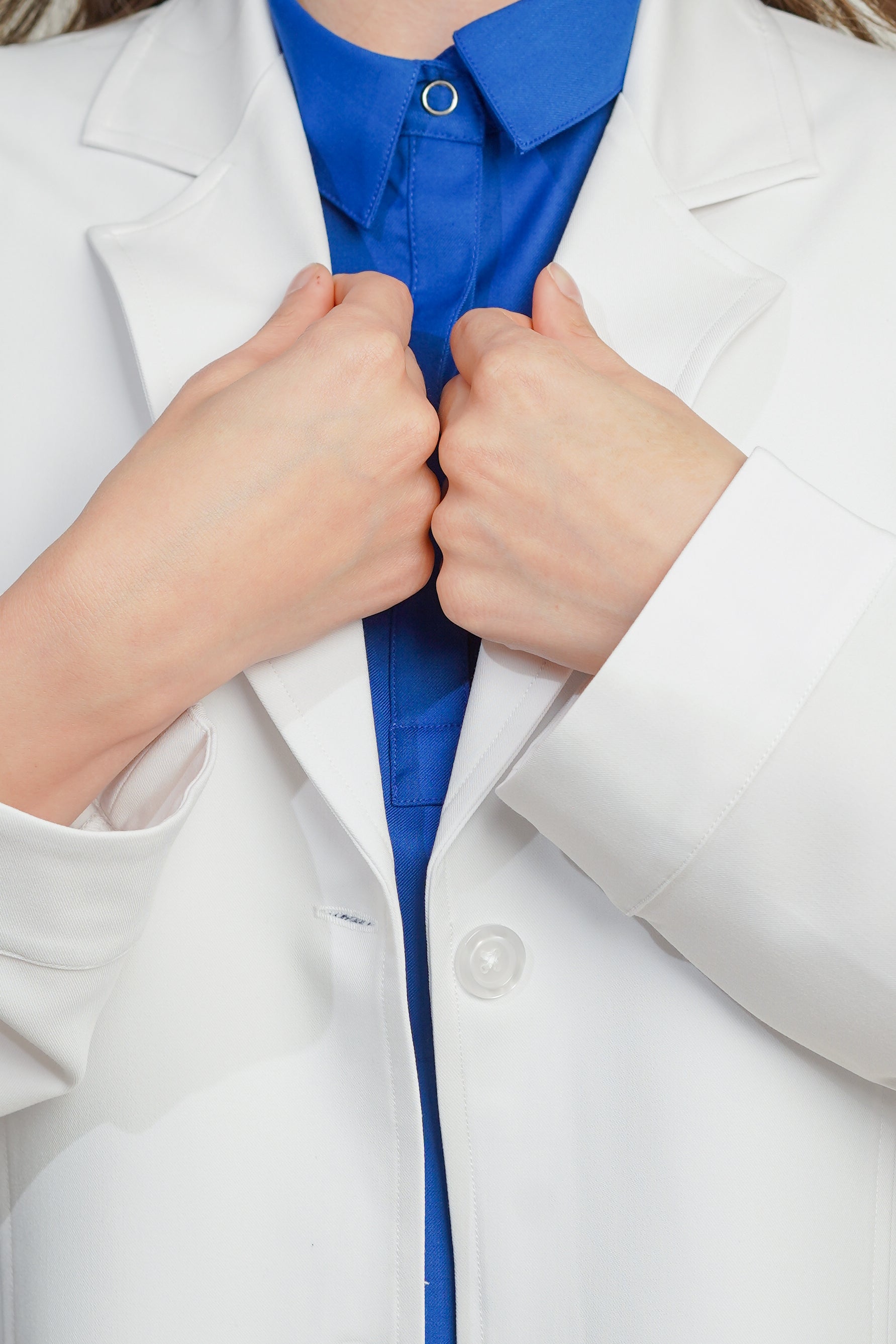 Person wearing a white lab coat over a blue shirt