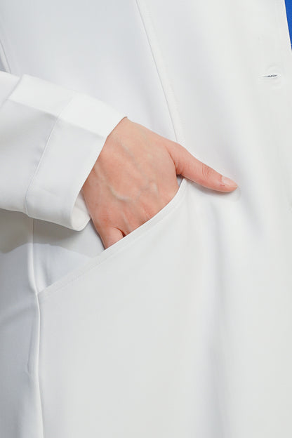 Close-up of a hand in a white coat pocket against a light background