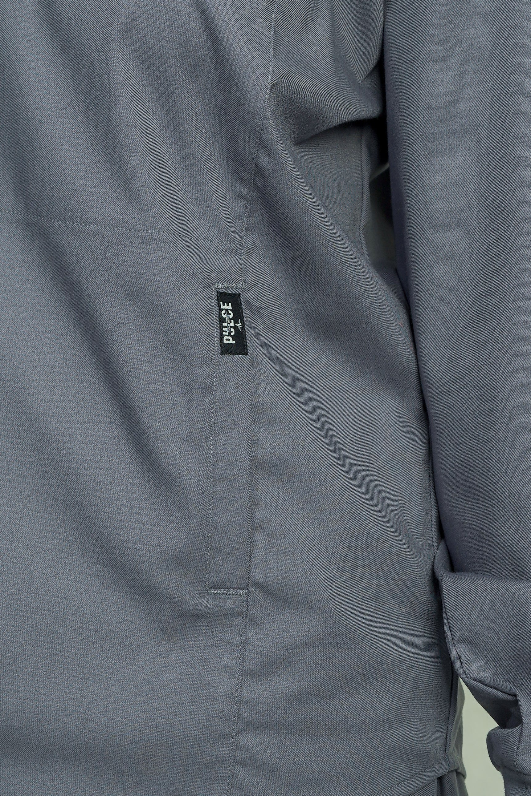 Close-up of a gray jacket with a visible brand label on a light green background