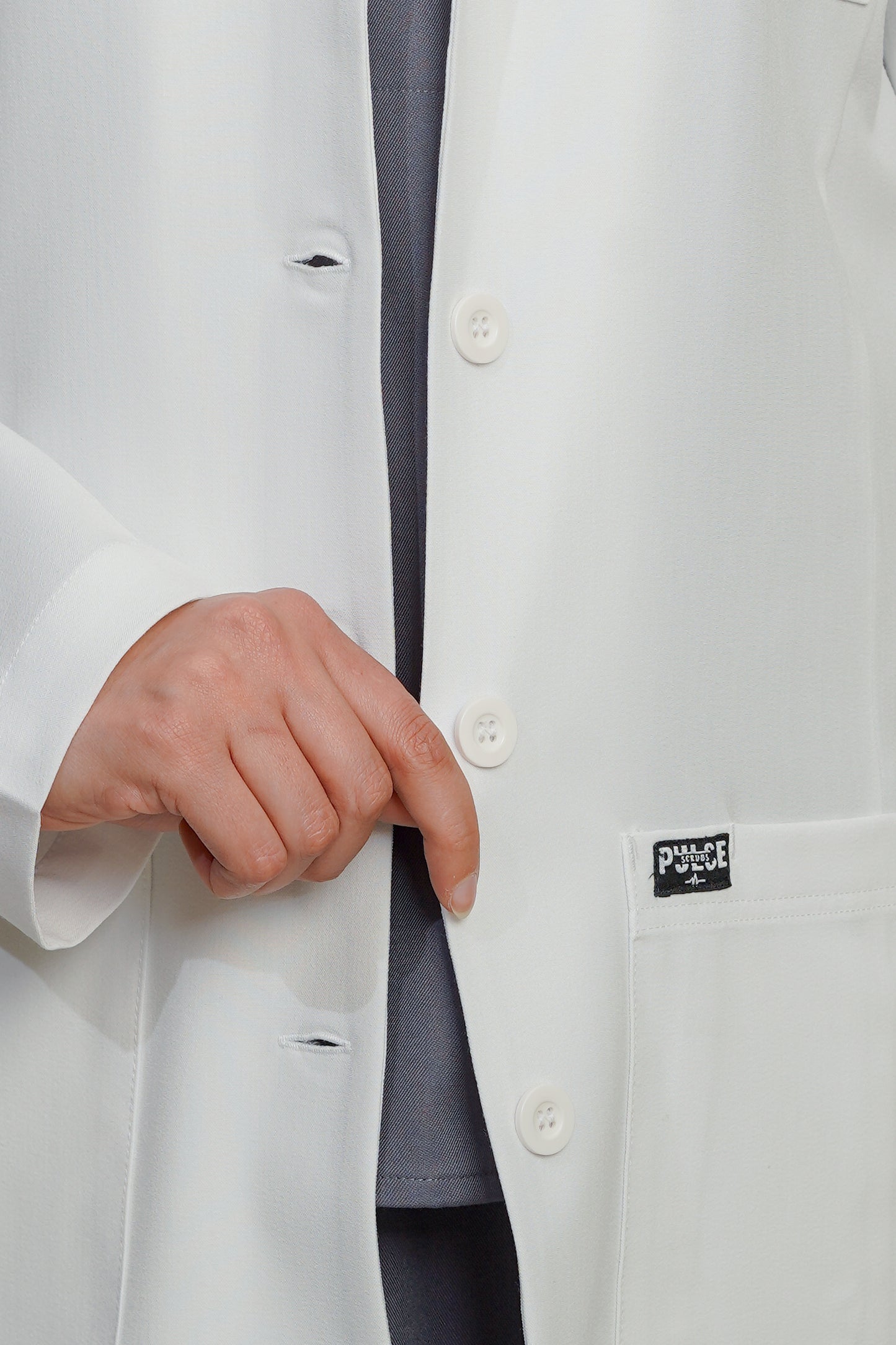 Close-up of a white lab coat with a brand label on the chest pocket.