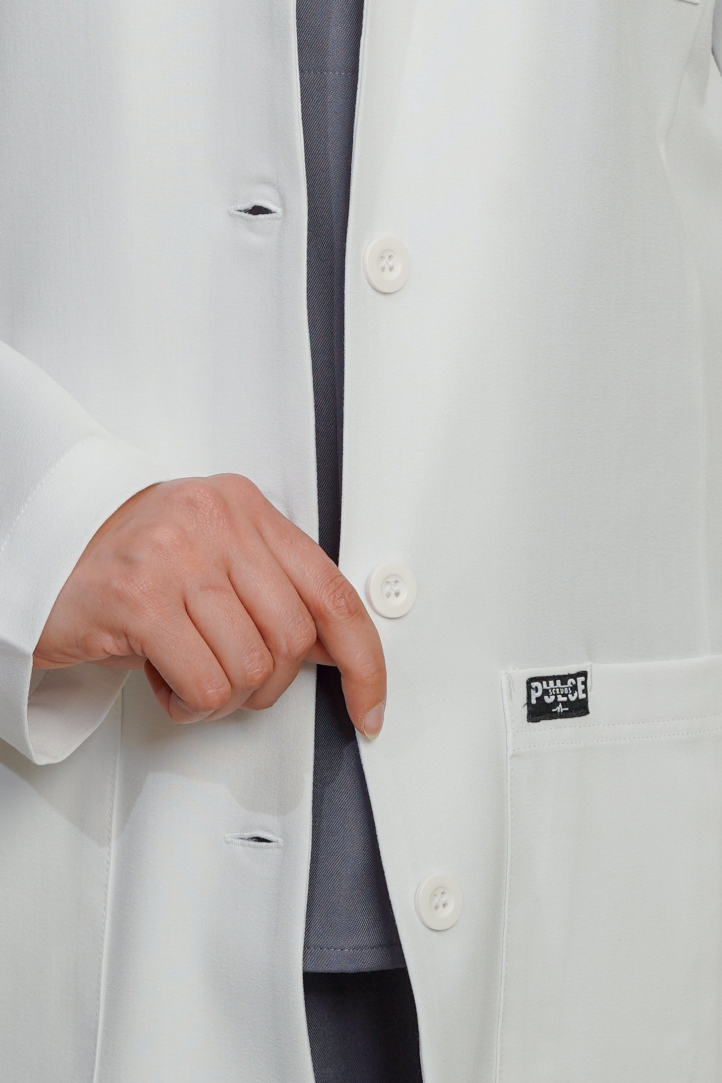 Close-up of a white lab coat with a brand label on the chest pocket.