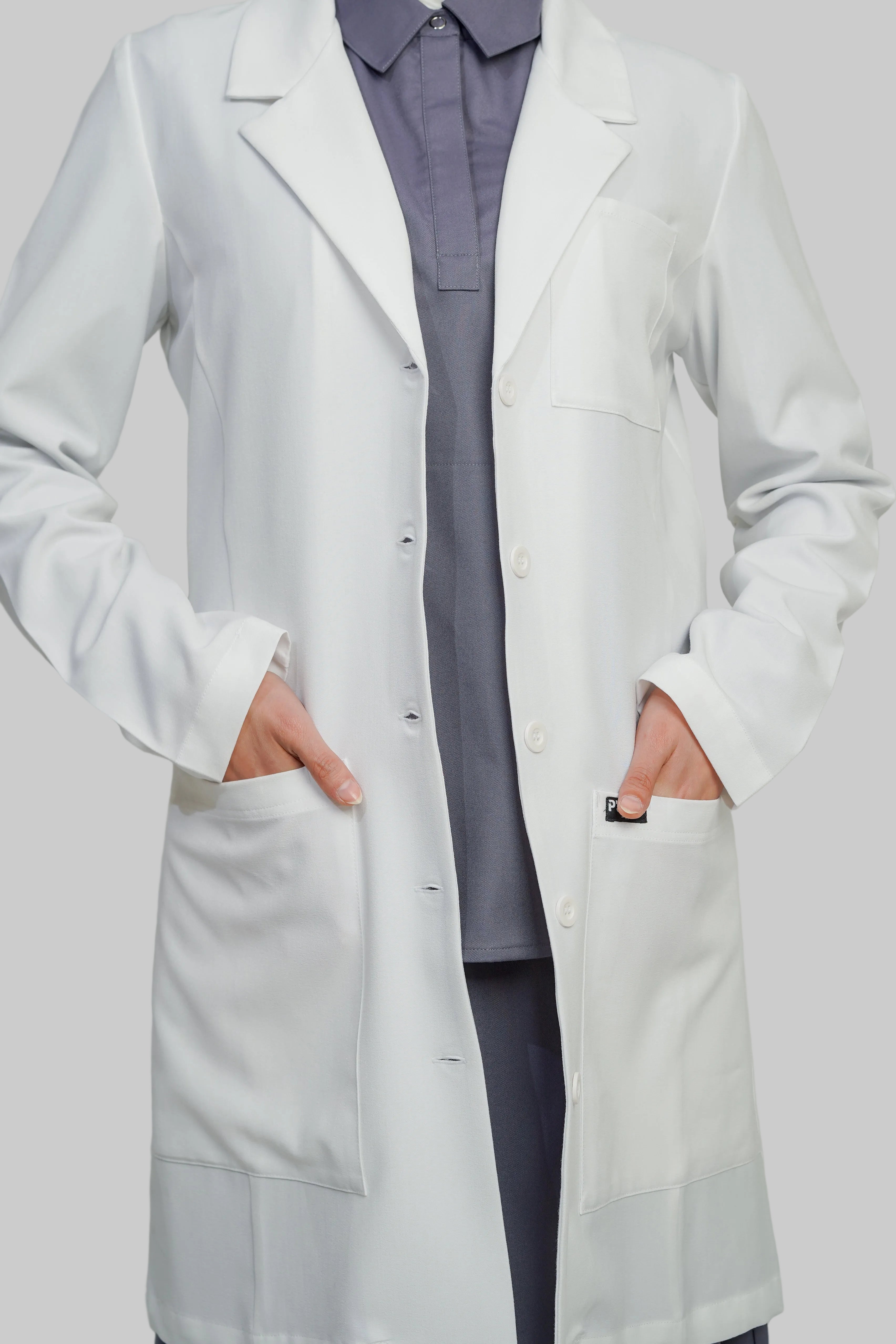Person wearing a white lab coat over a gray outfit on a plain background