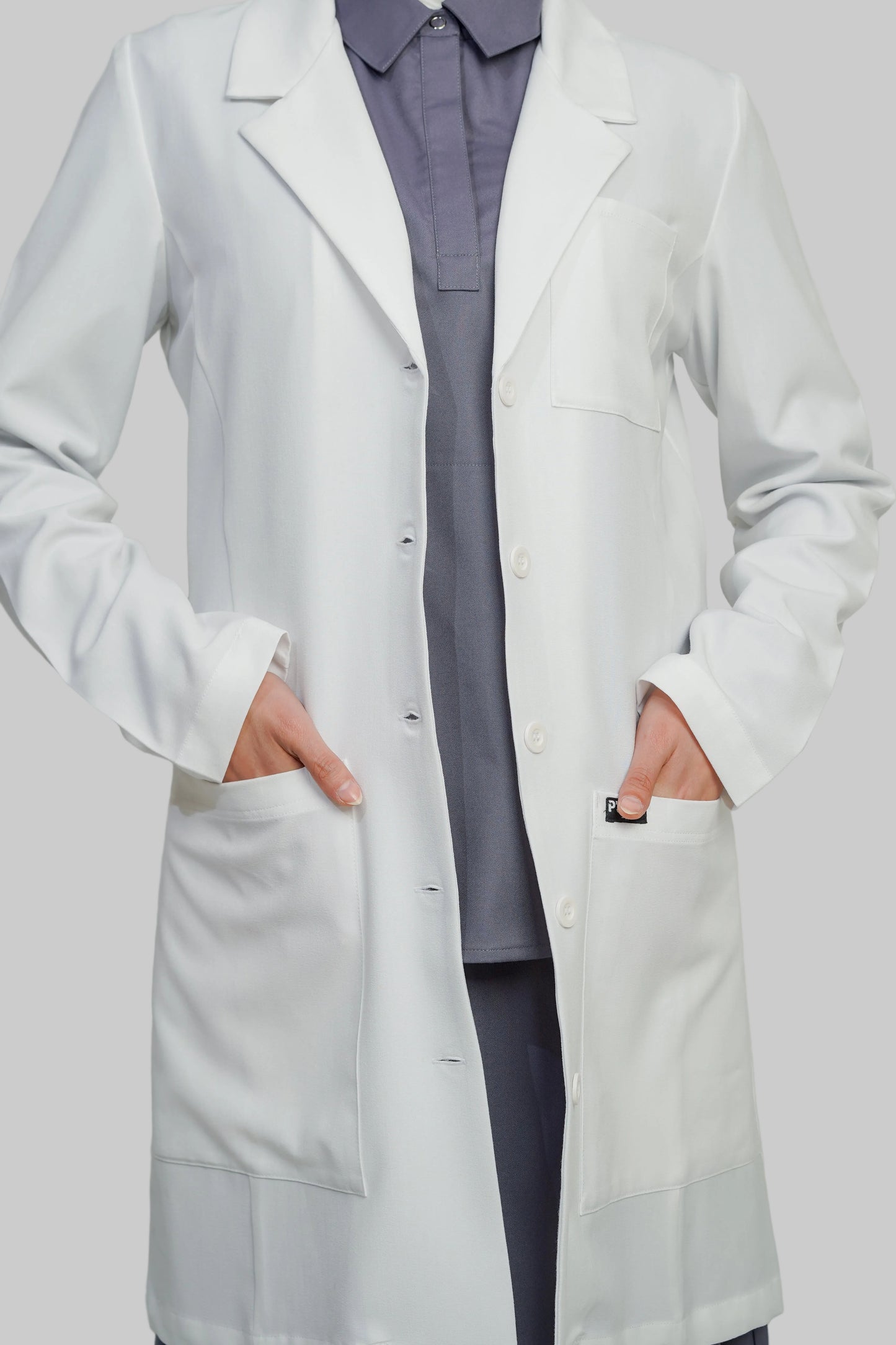 Person wearing a white lab coat over a gray outfit on a plain background