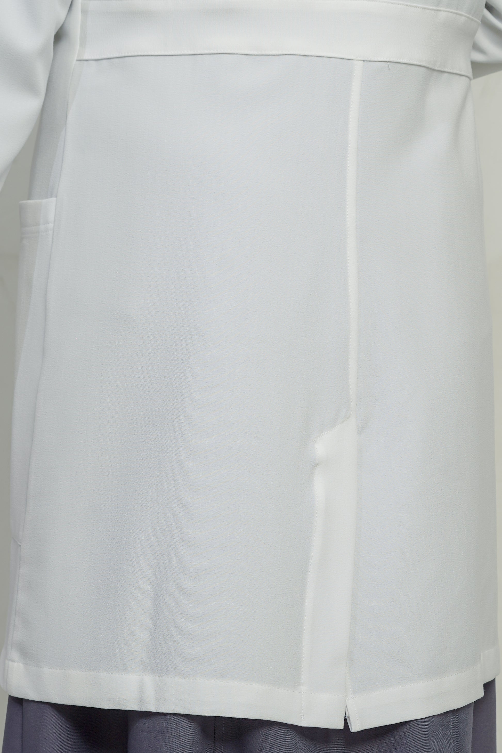 Close-up of a light gray coat with a pocket on a plain background