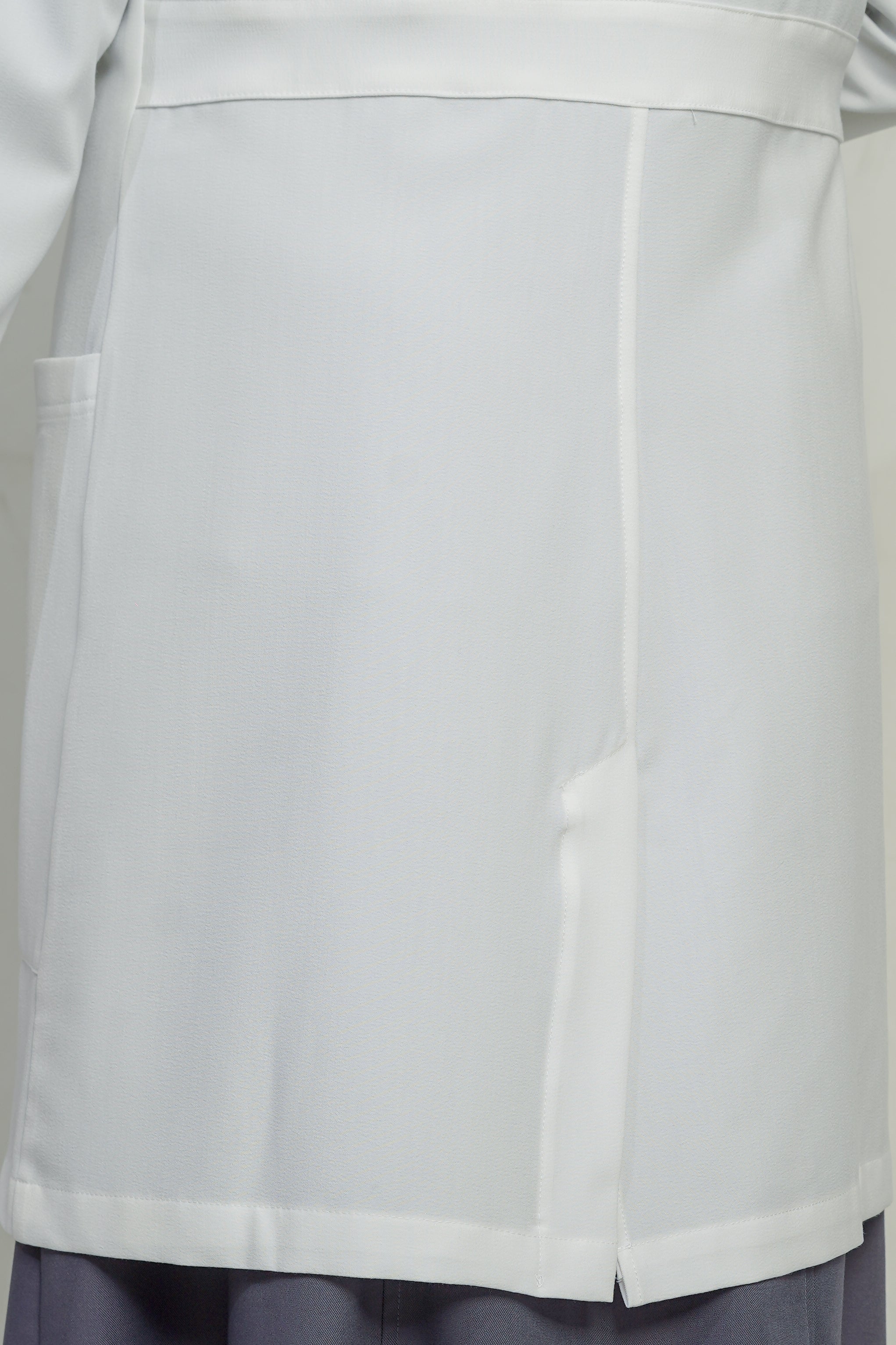 Close-up of a light gray coat with a pocket on a plain background