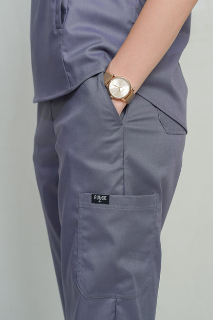 Person wearing gray pants with a visible brand logo on a plain background