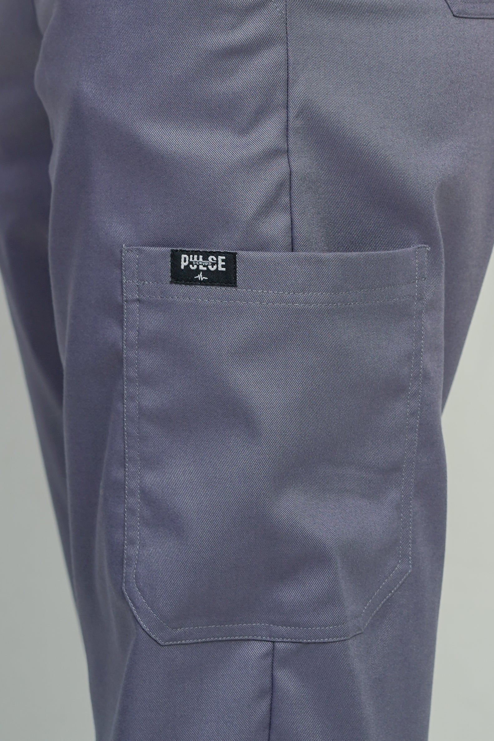 Close-up of a pocket on a pair of gray pants with a visible brand label.