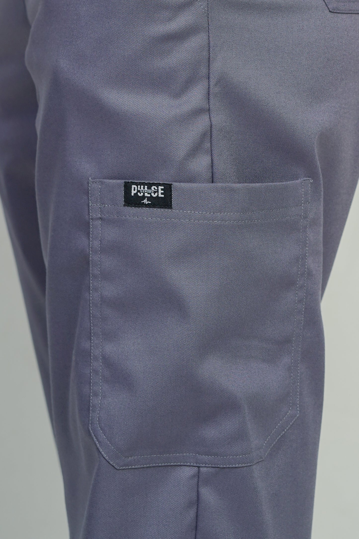 Close-up of a pocket on a pair of gray pants with a visible brand label.
