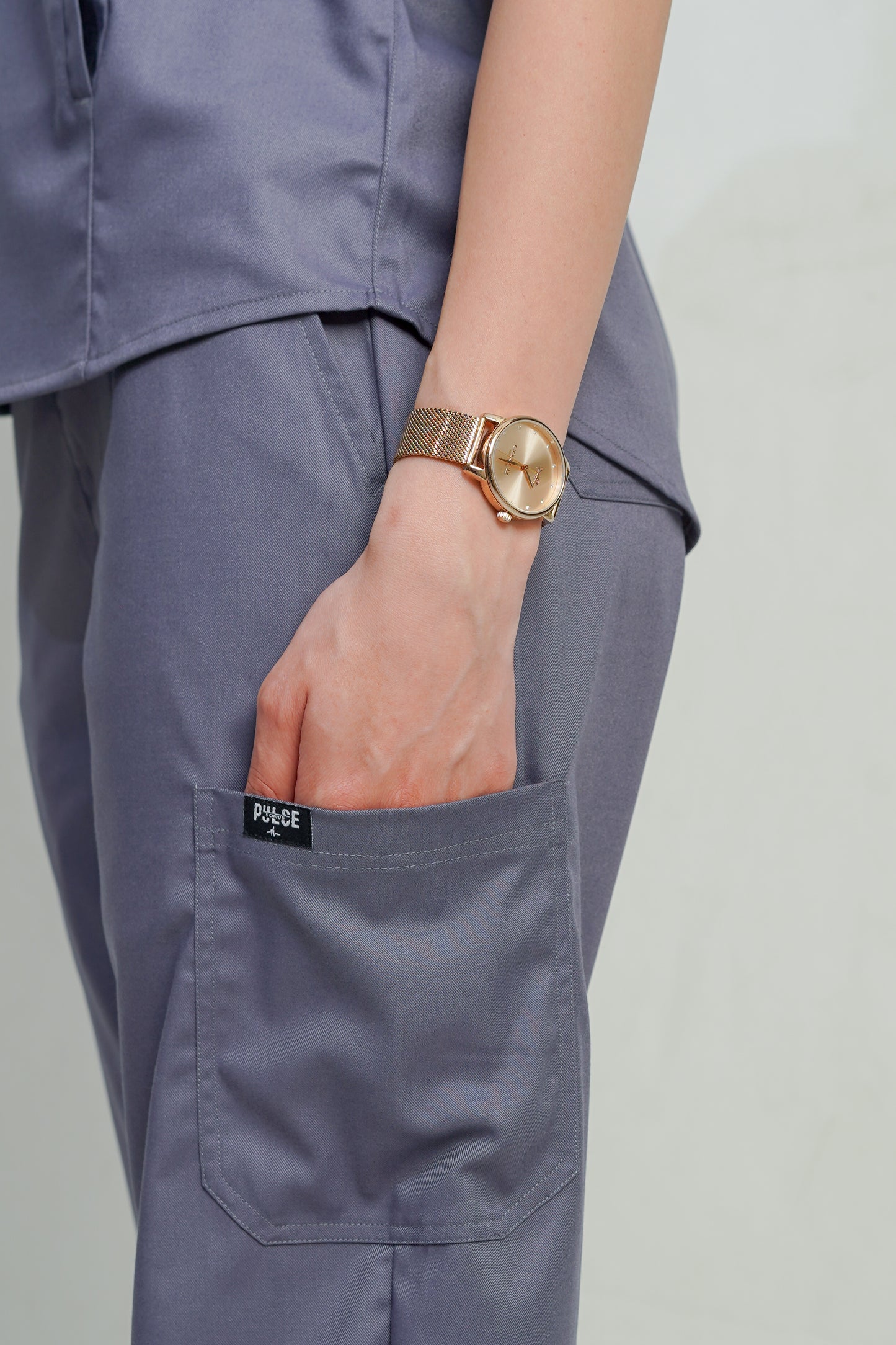 Person wearing a gold watch on a plain background