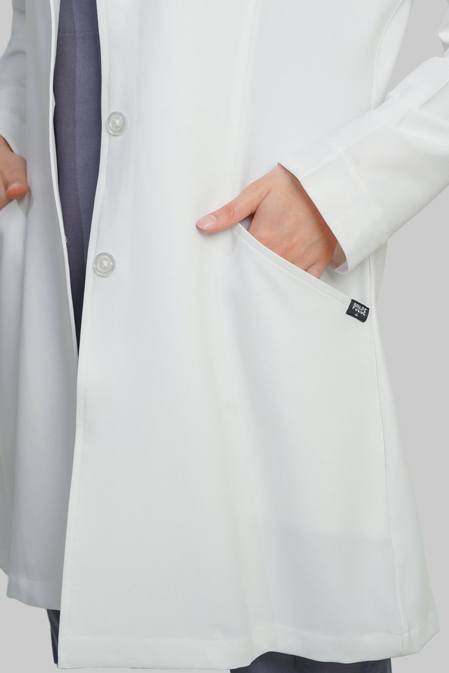 Person wearing a white lab coat with a visible brand label on a plain background