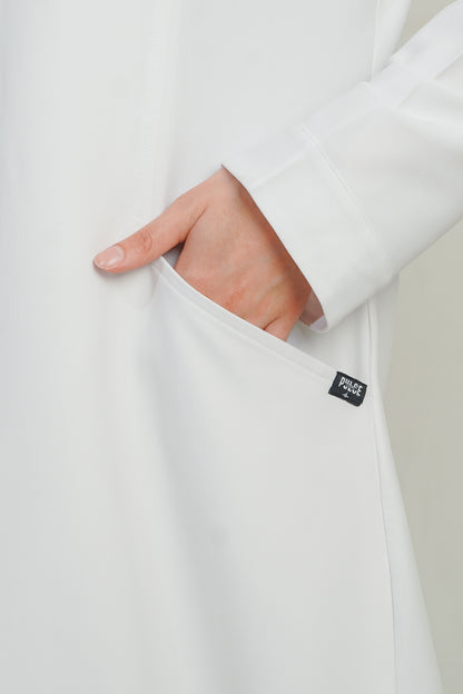 Close-up of a white garment with a visible brand label on a plain background