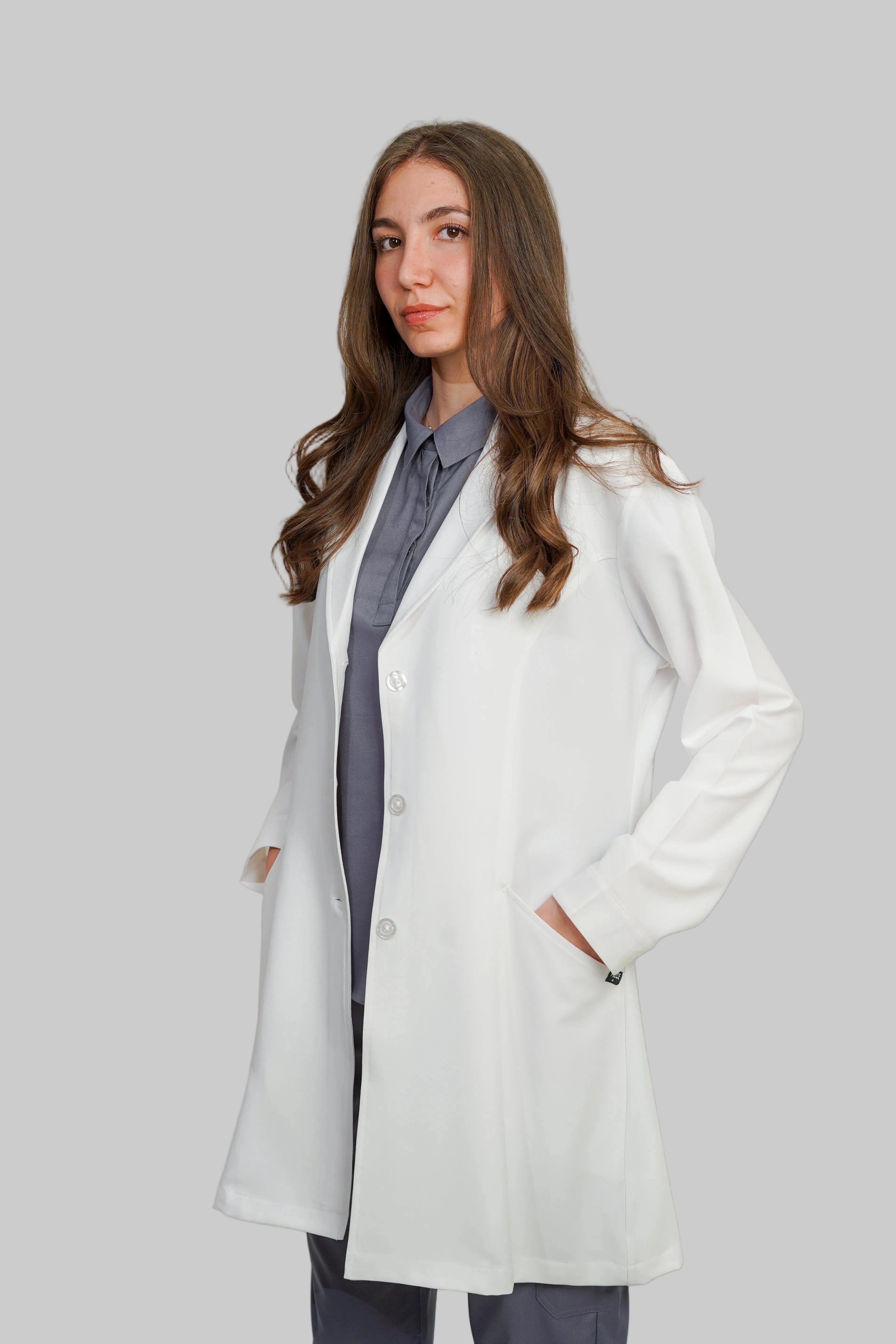Person wearing a white lab coat over a gray outfit on a plain background