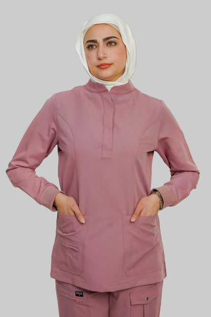 Person wearing a pink scrub set with a hijab on a plain background