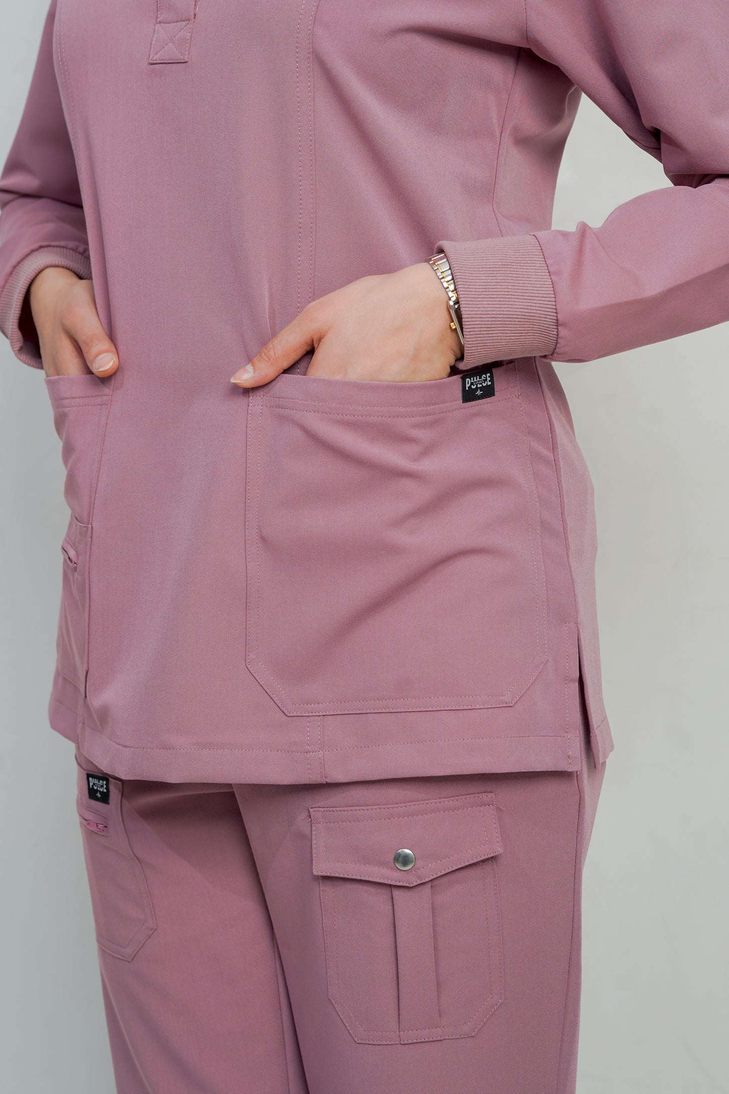 Person wearing a pink scrub set with a plain background