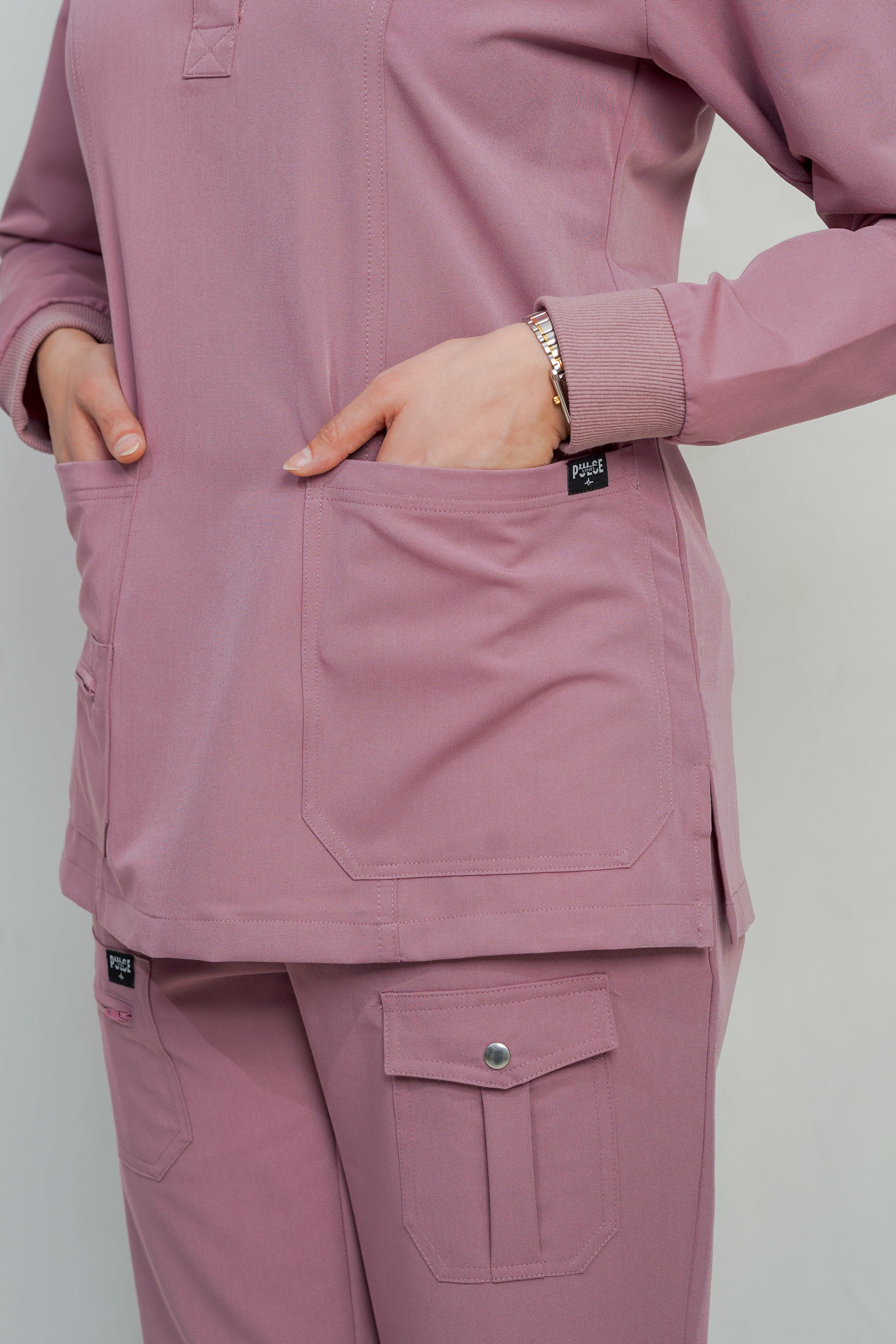 Person wearing a pink scrub set with a plain background