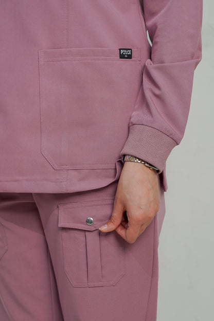 Close-up of a person wearing a pink scrub set with a visible brand logo on a plain background