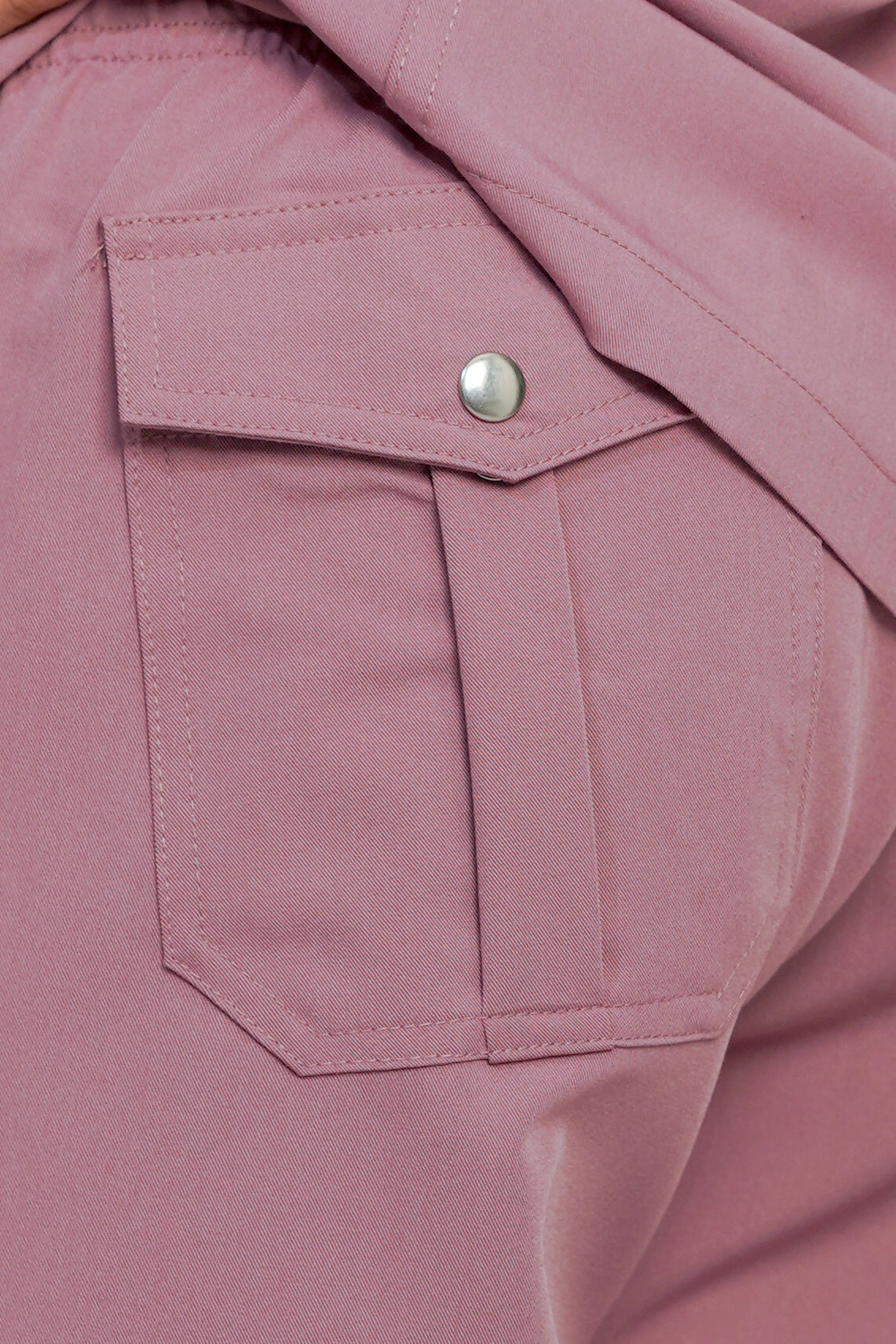 Close-up of a pink jacket with a button on a matching fabric background