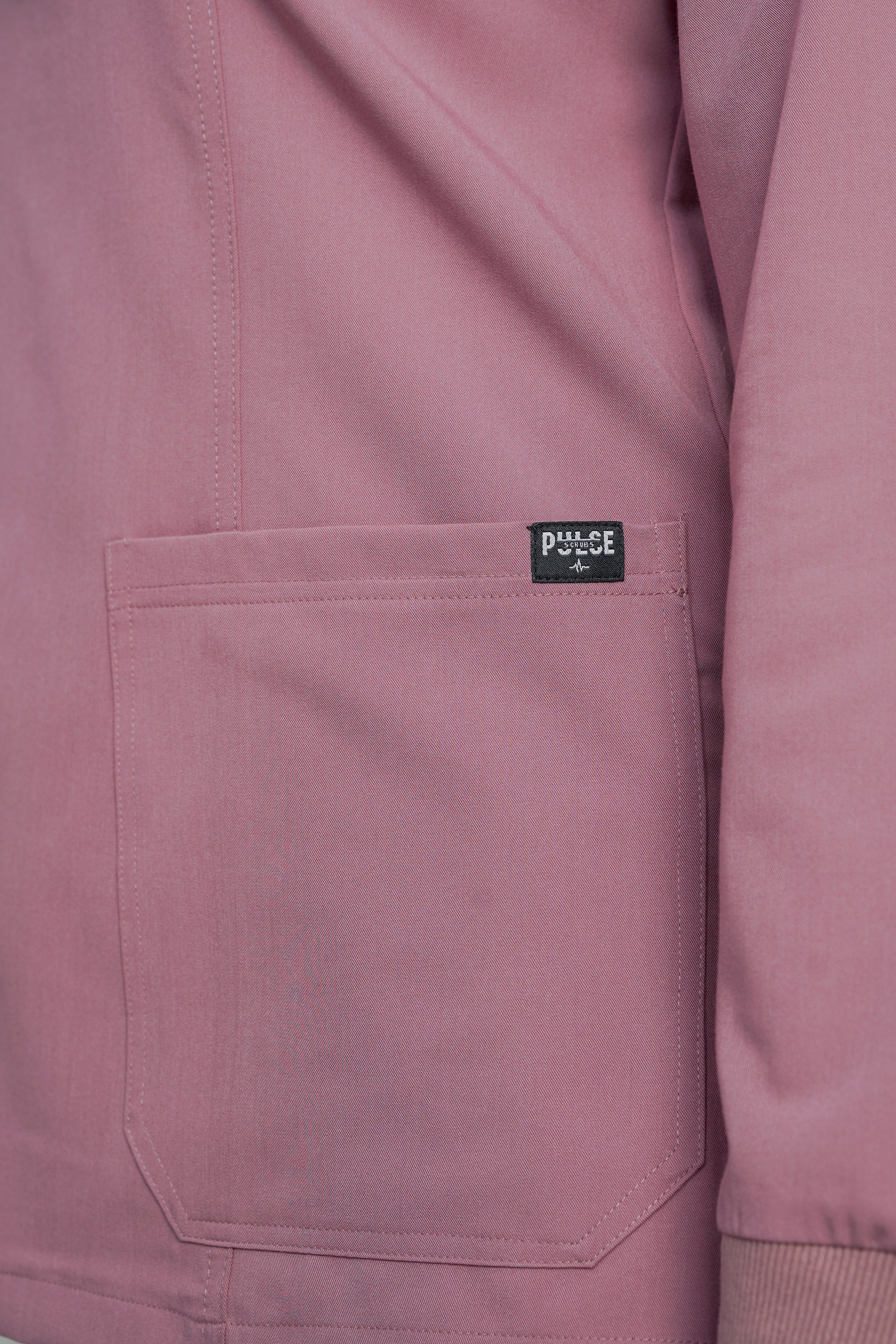 Close-up of a pink jacket with a brand label on the chest pocket.