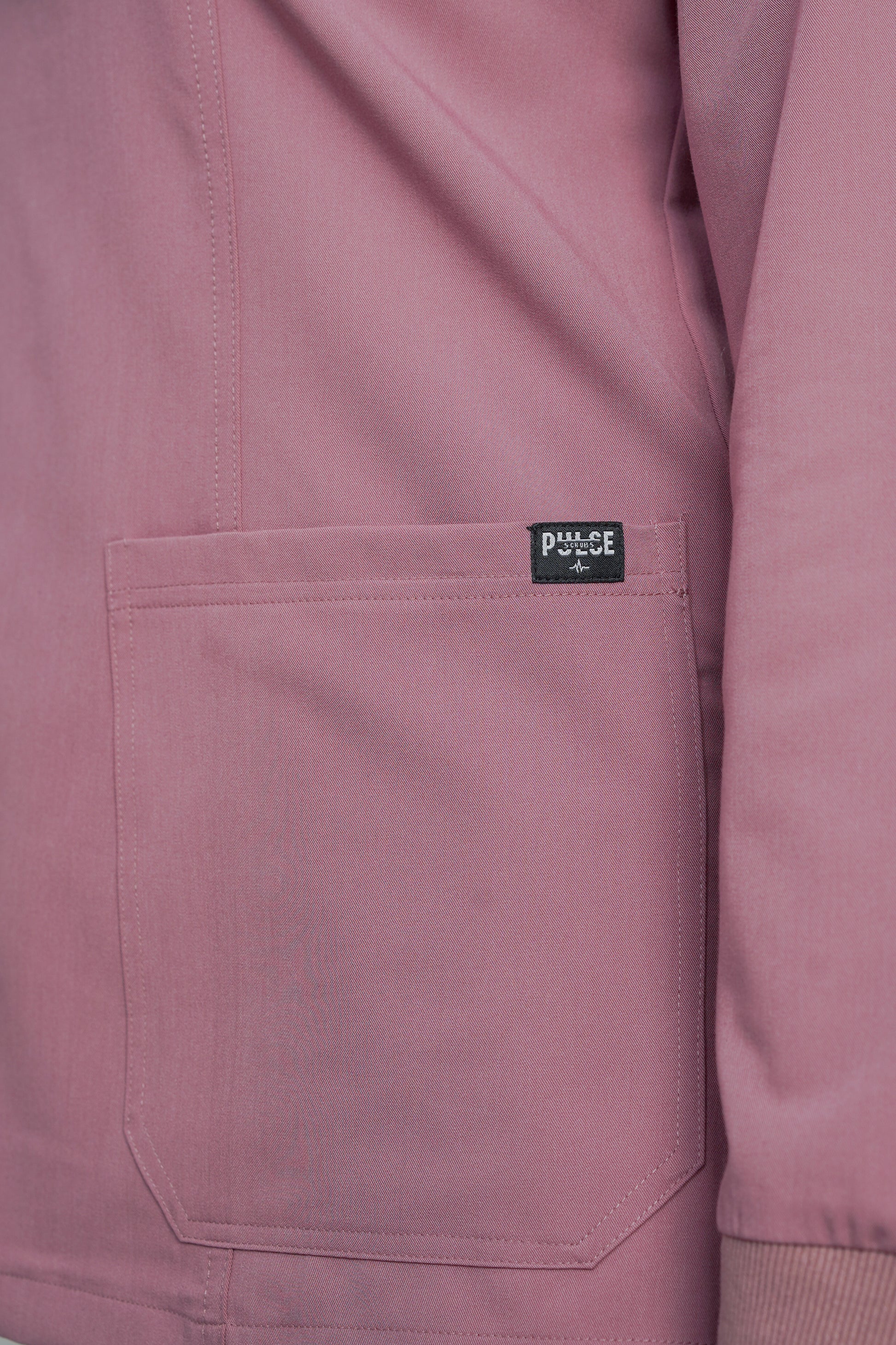 Close-up of a pink jacket with a brand label on the chest pocket.