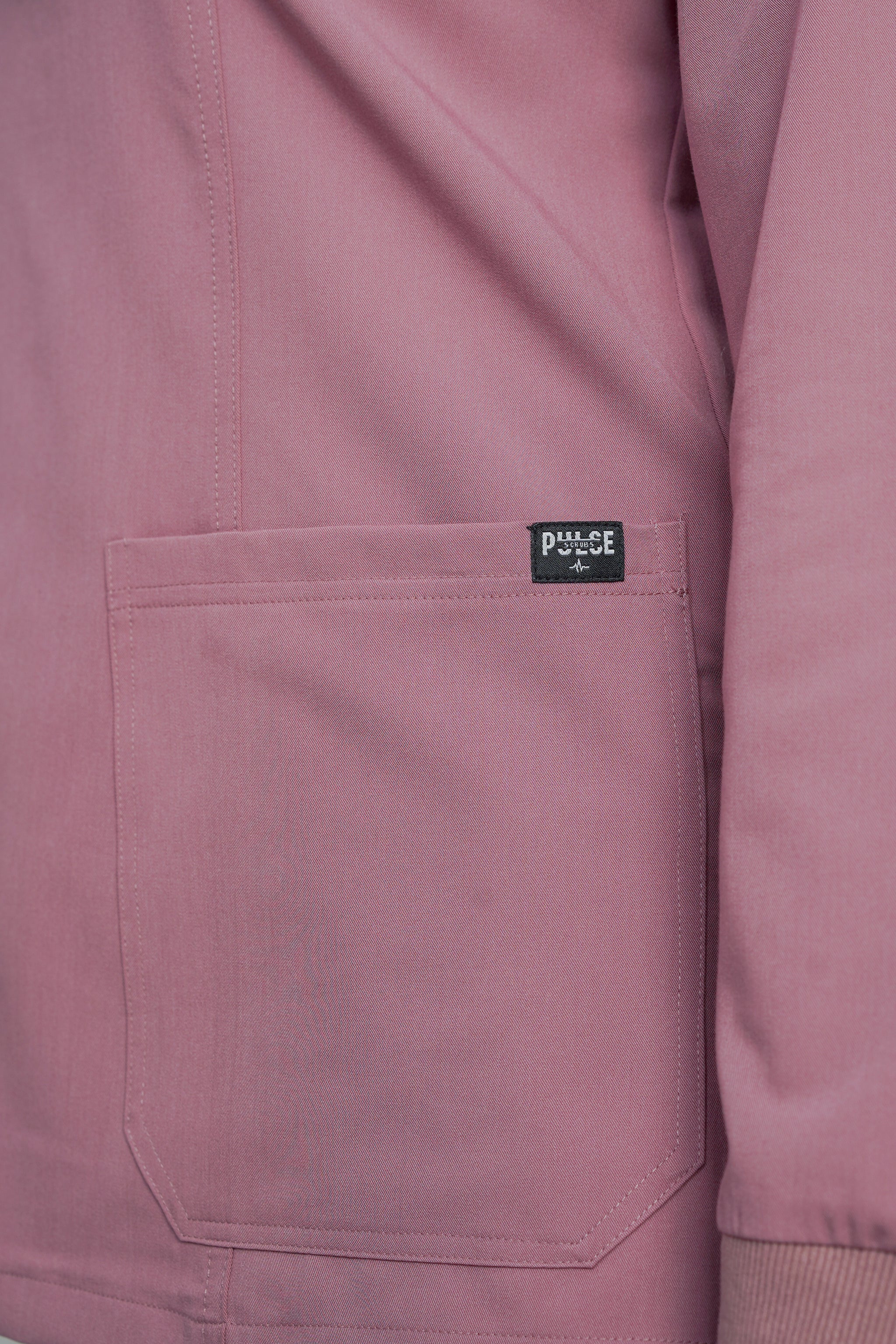 Close-up of a pink jacket with a brand label on the chest pocket.