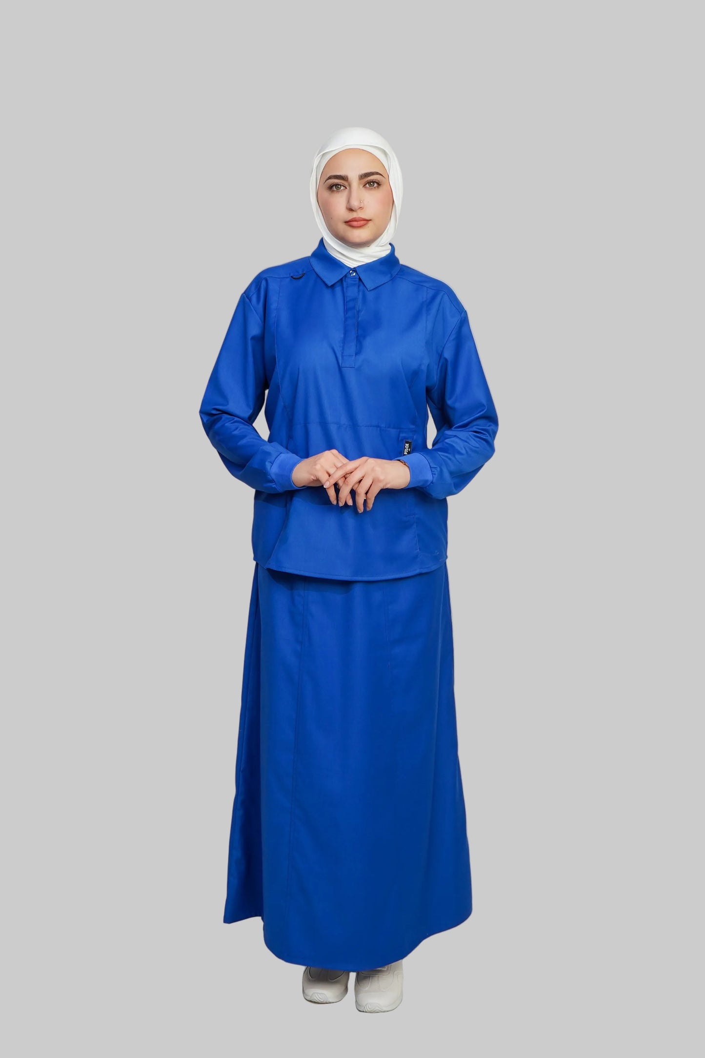 Person wearing a blue outfit with a white hijab on a gray background