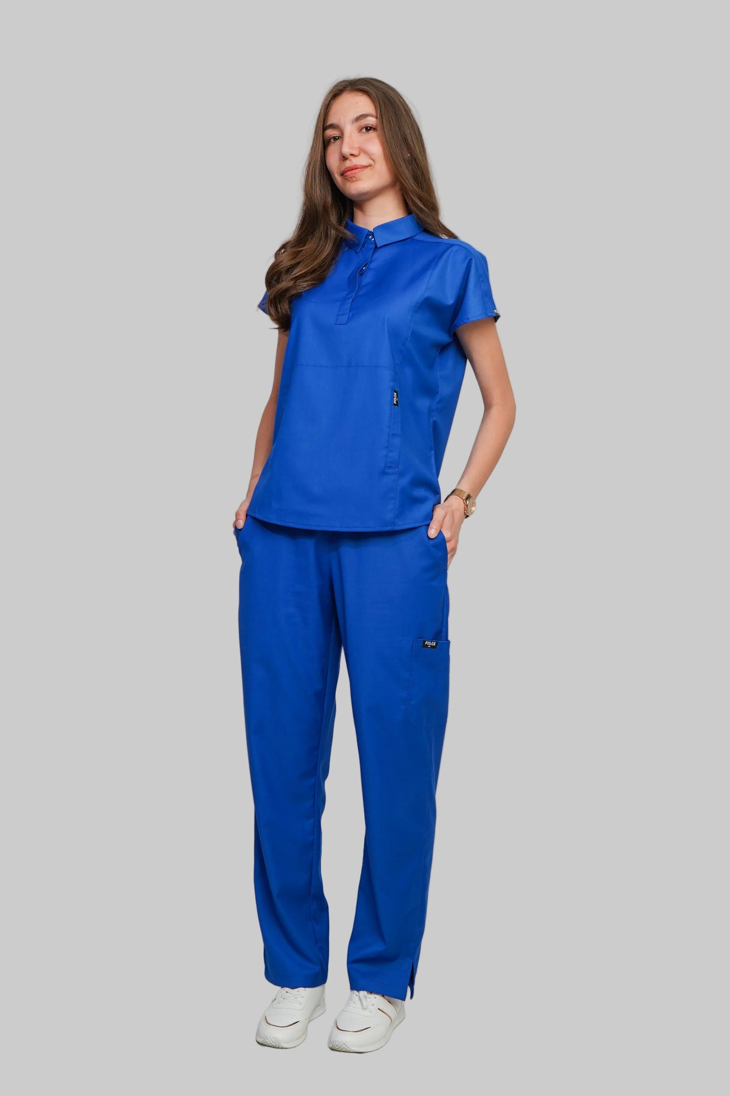 Woman wearing a blue scrub set against a plain background