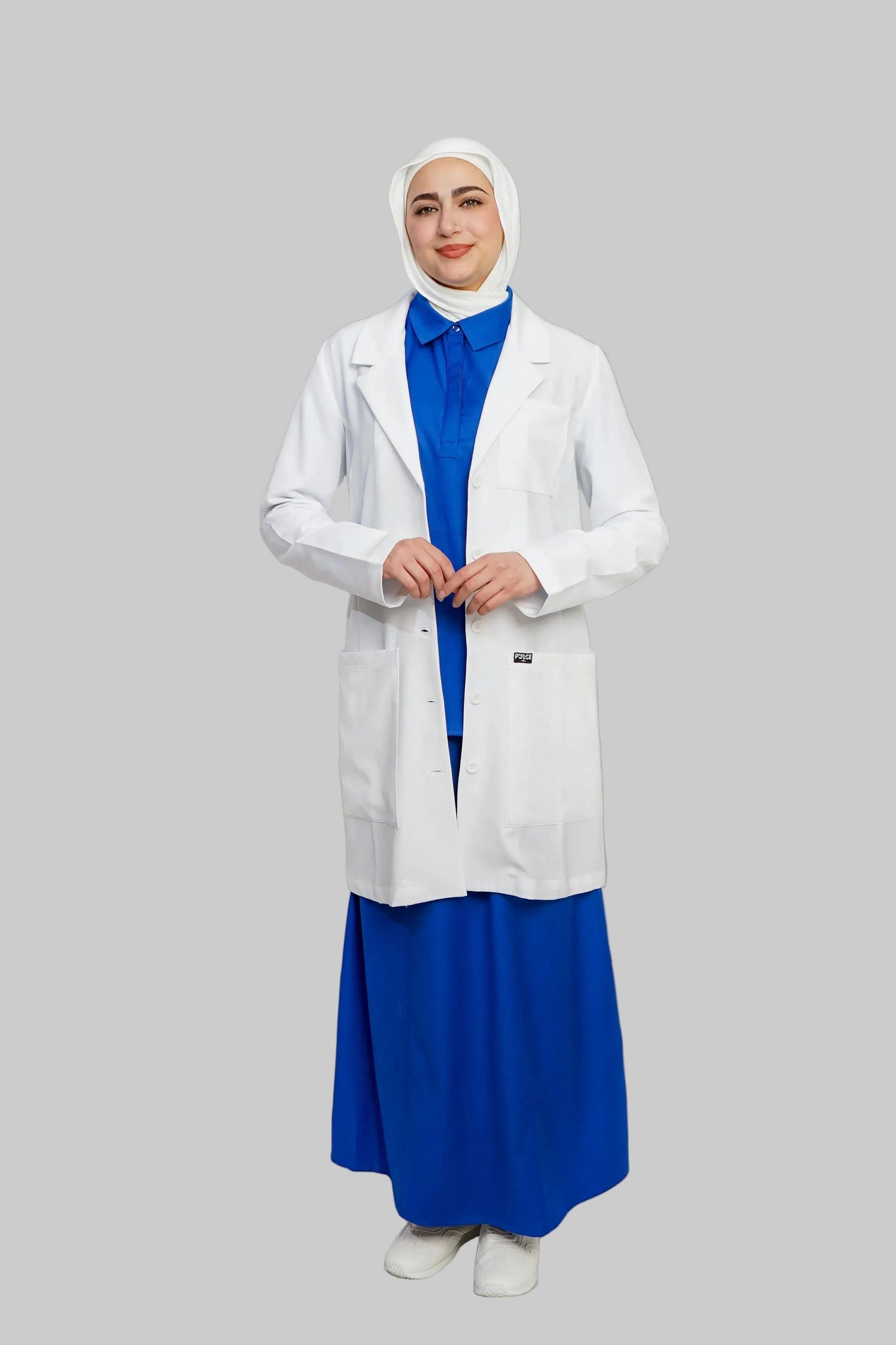 Person wearing a white lab coat over a blue dress on a plain background