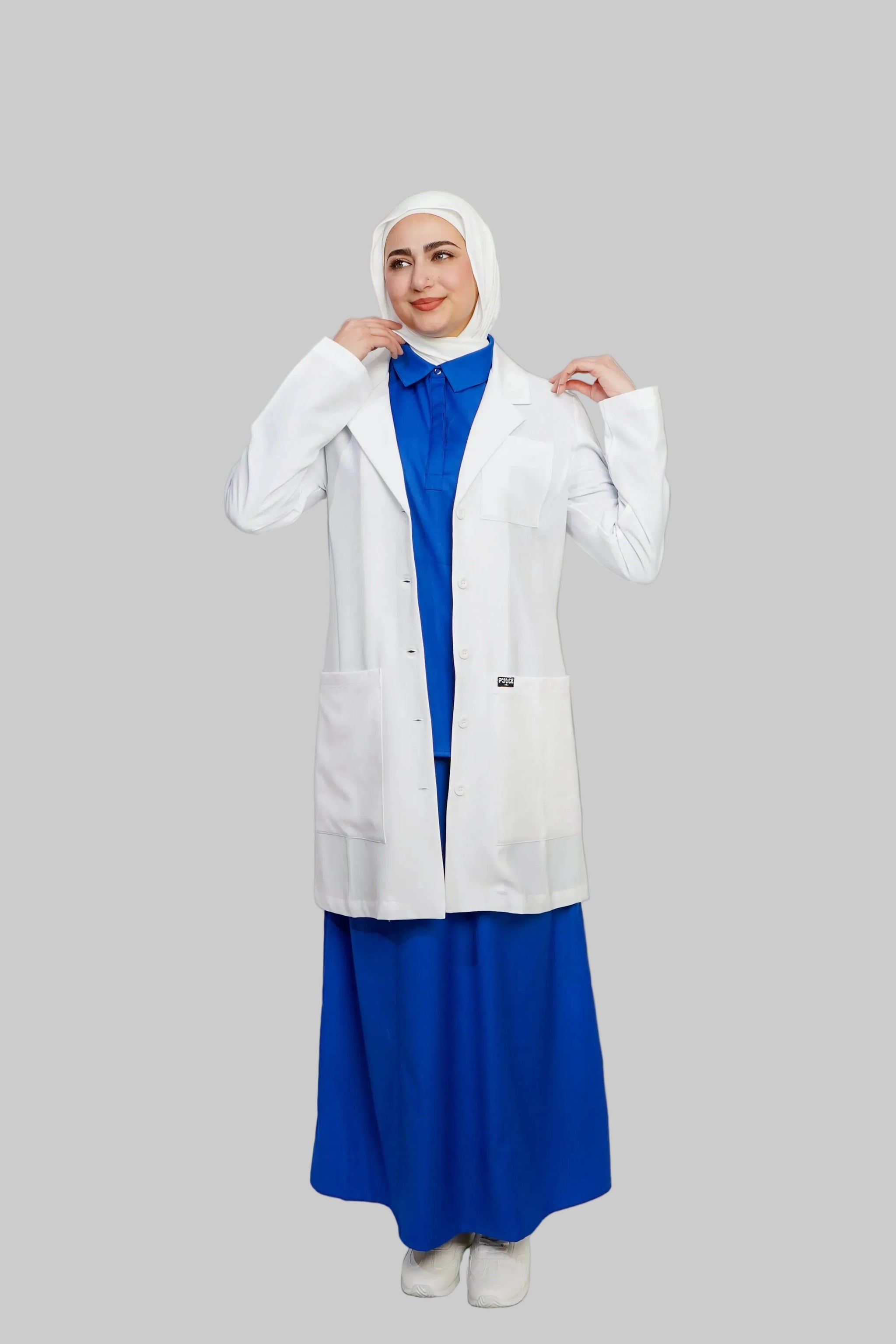 Person wearing a white lab coat over a blue outfit on a plain background