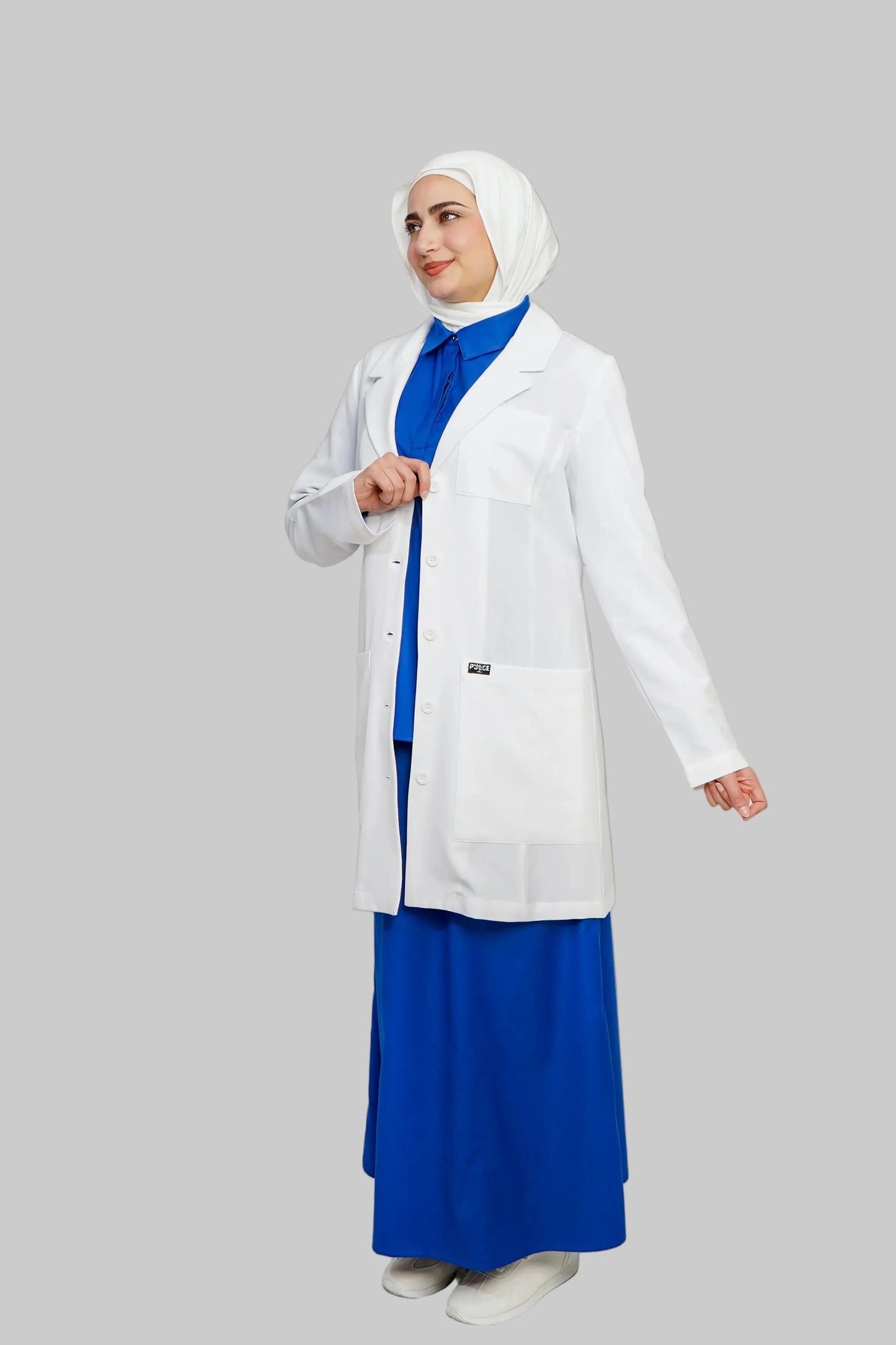 Person wearing a white lab coat over a blue dress on a plain background