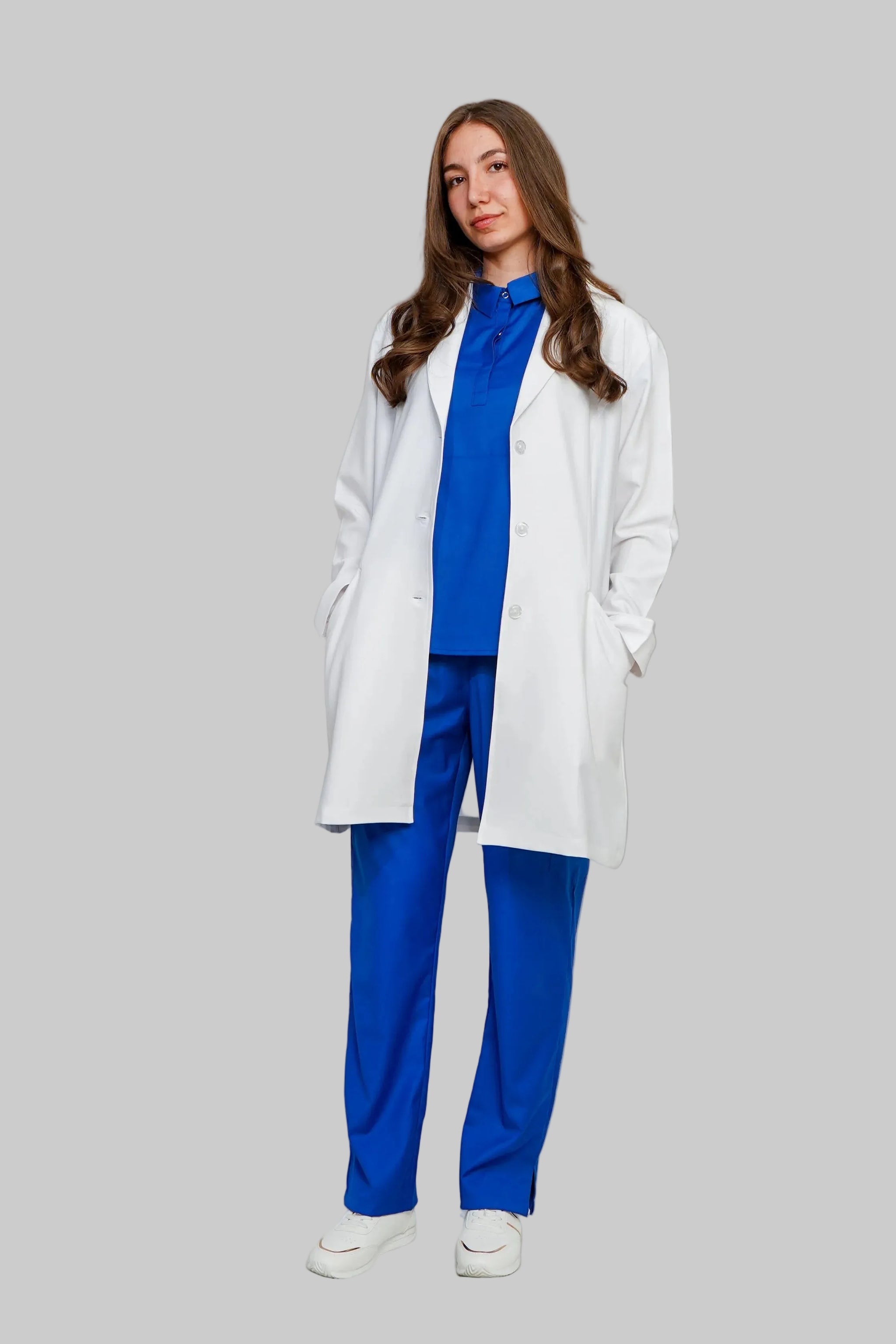 Woman wearing a white coat over a blue outfit on a plain background