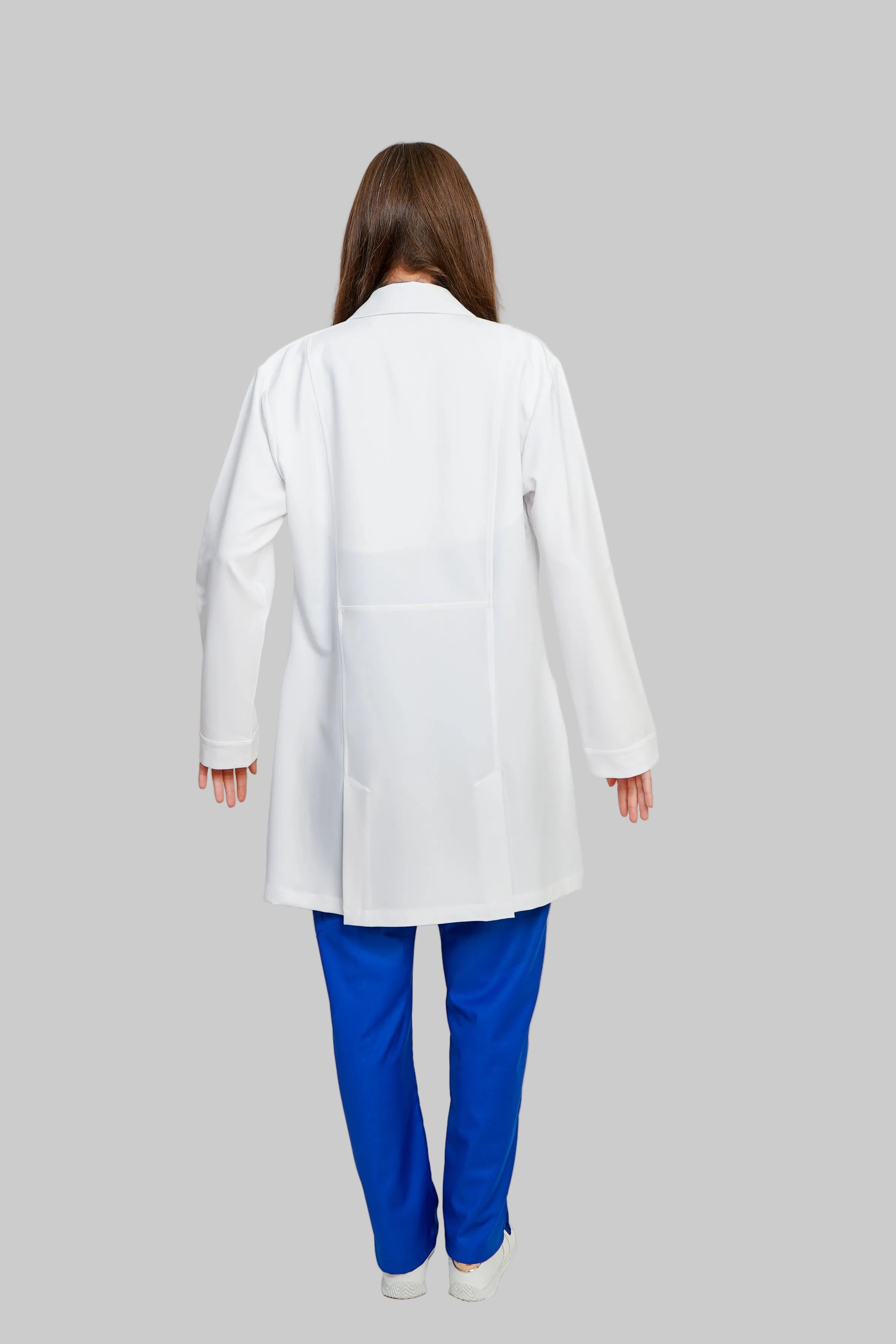 Person wearing a white lab coat and blue pants on a plain background