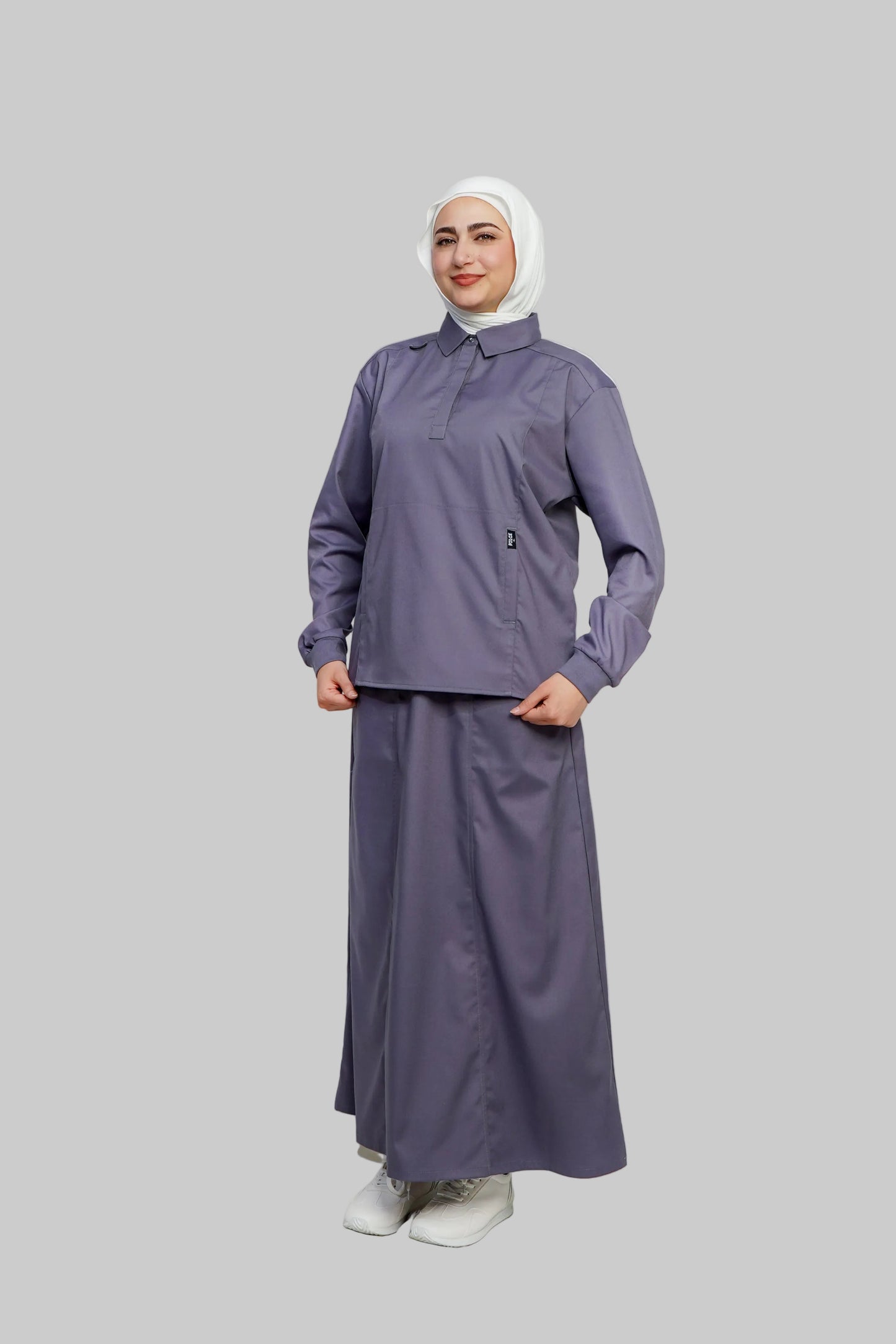 Woman wearing a purple outfit with a white hijab on a light gray background
