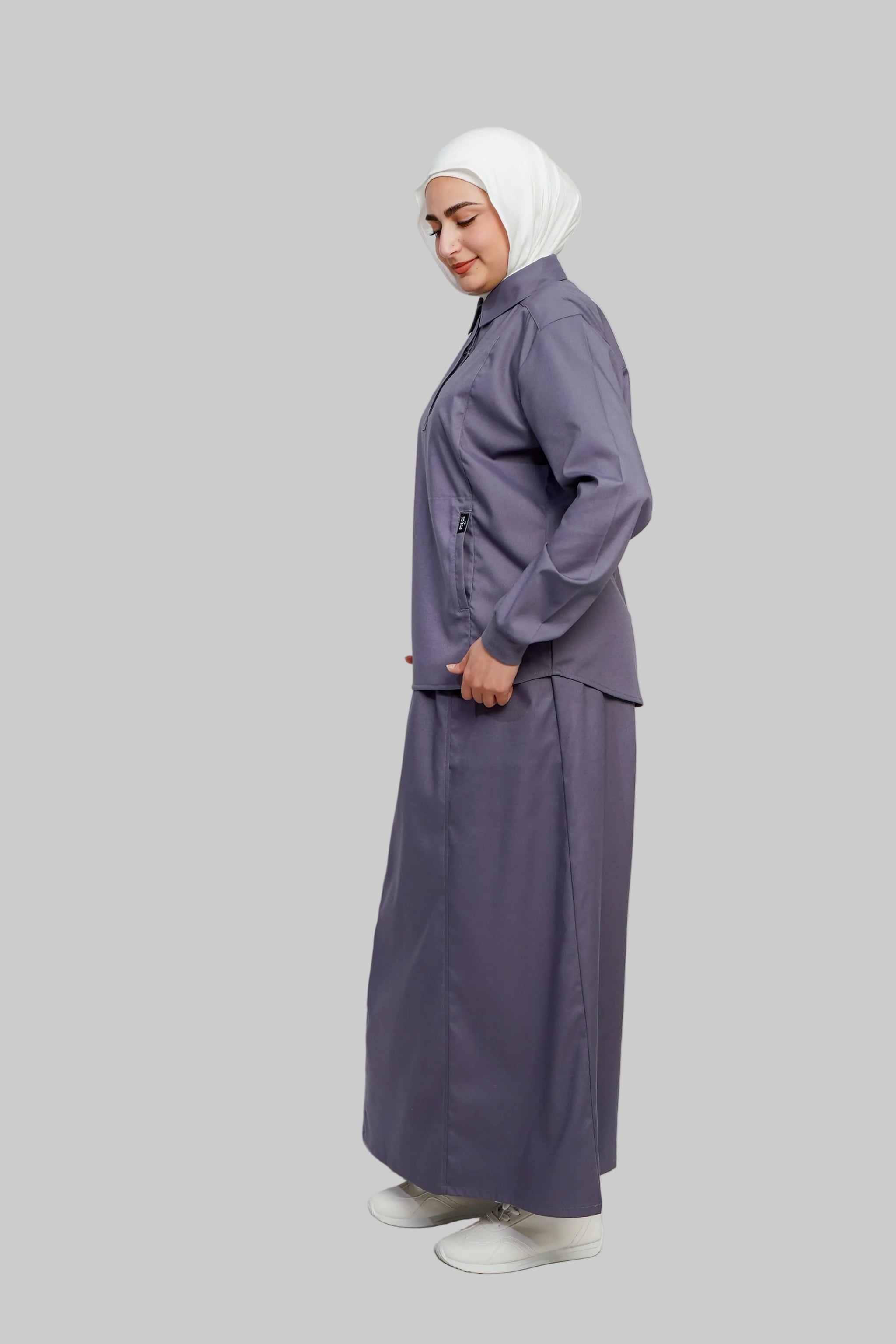 Person wearing a matching purple outfit with a hijab on a white background