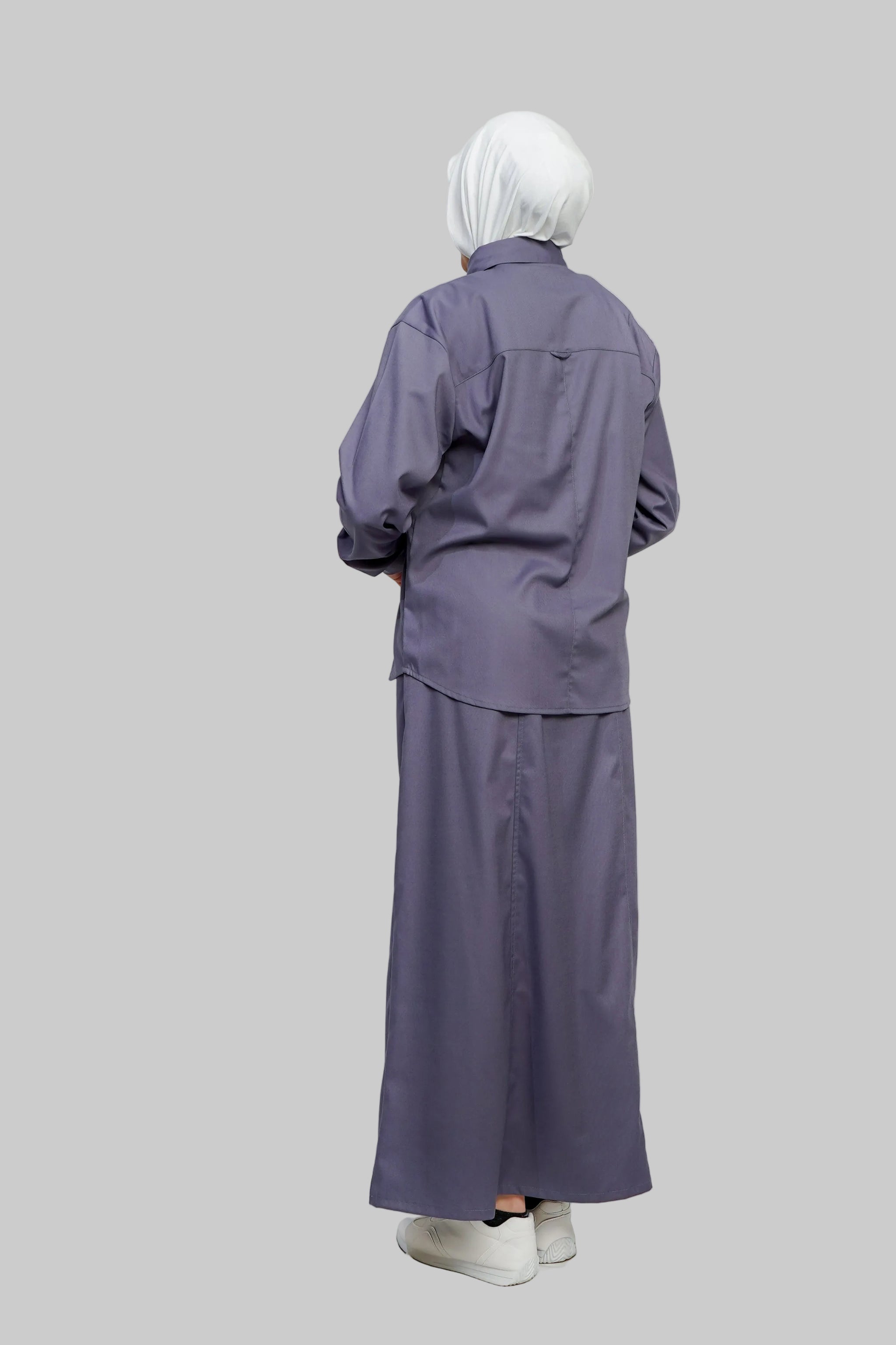 Person wearing a long-sleeve purple outfit with a matching headscarf on a white background
