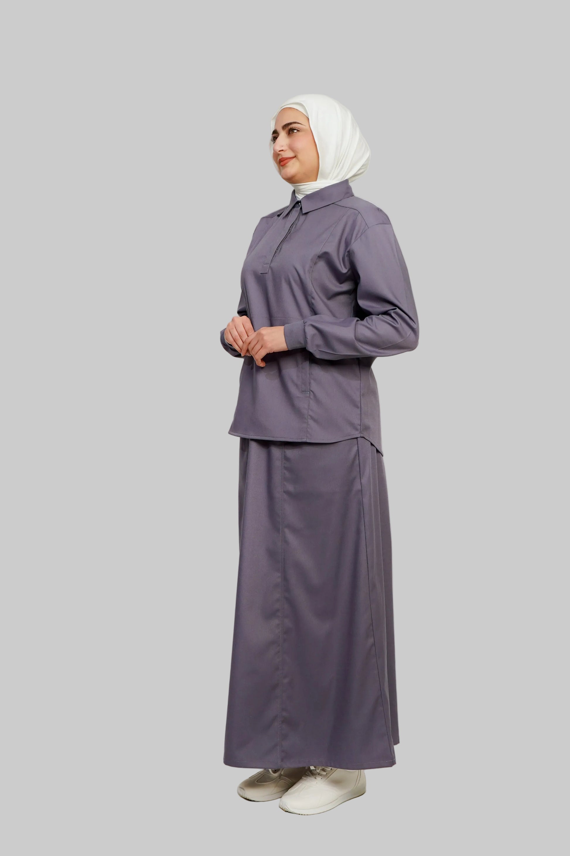 Woman wearing a matching outfit with a hijab against a plain background