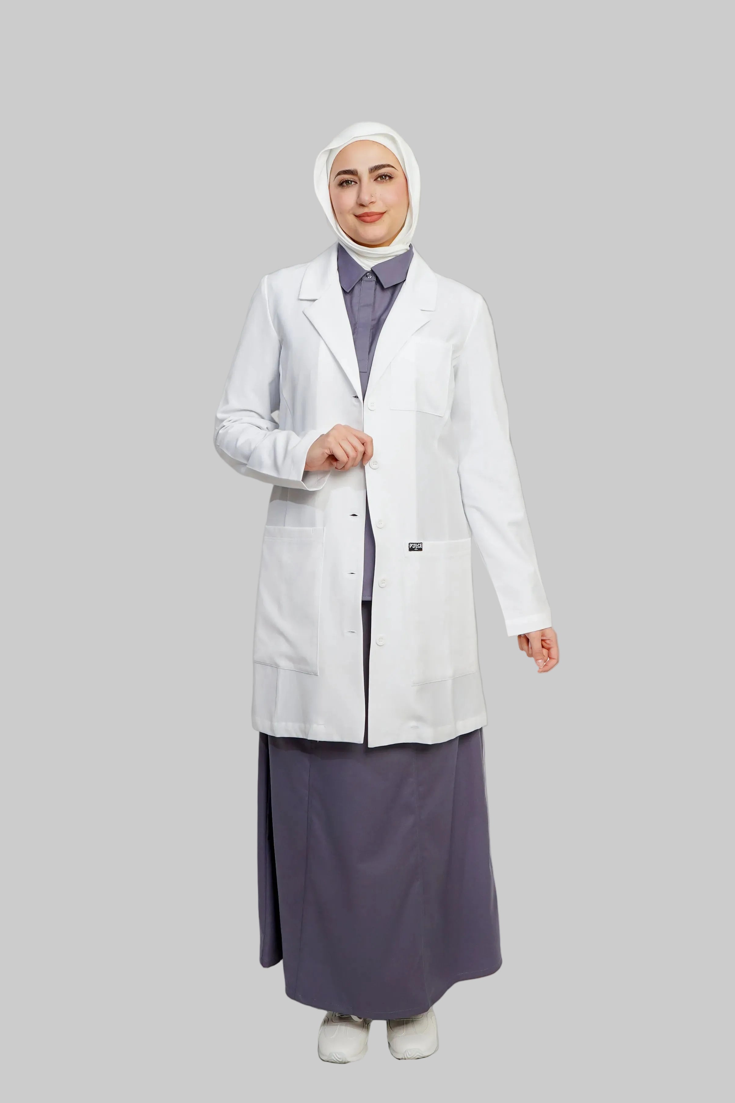 Person wearing a white lab coat over a long dark skirt on a plain background