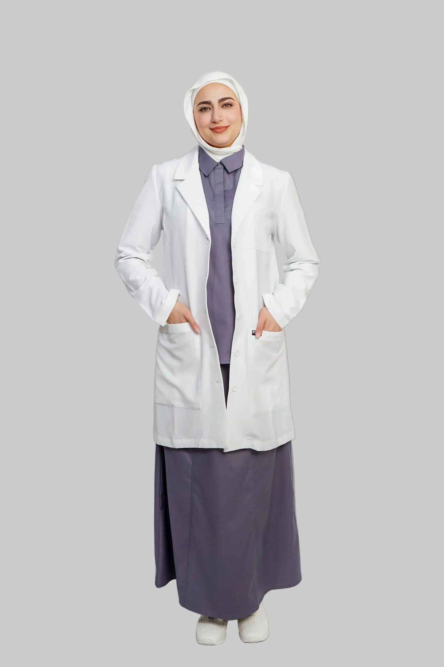 Person wearing a white lab coat over a long purple dress on a light gray background