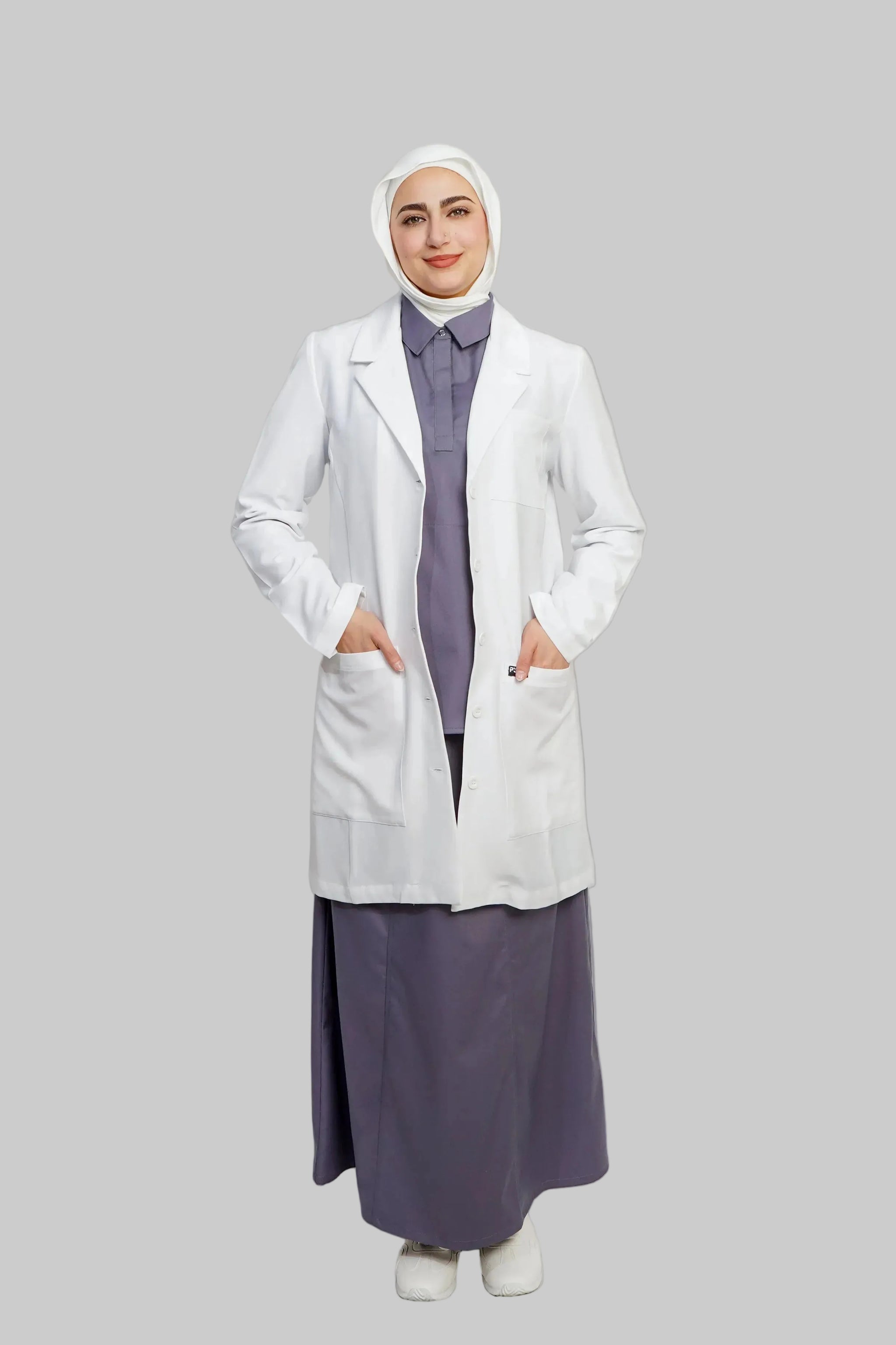 Person wearing a white lab coat over a long purple dress on a light gray background