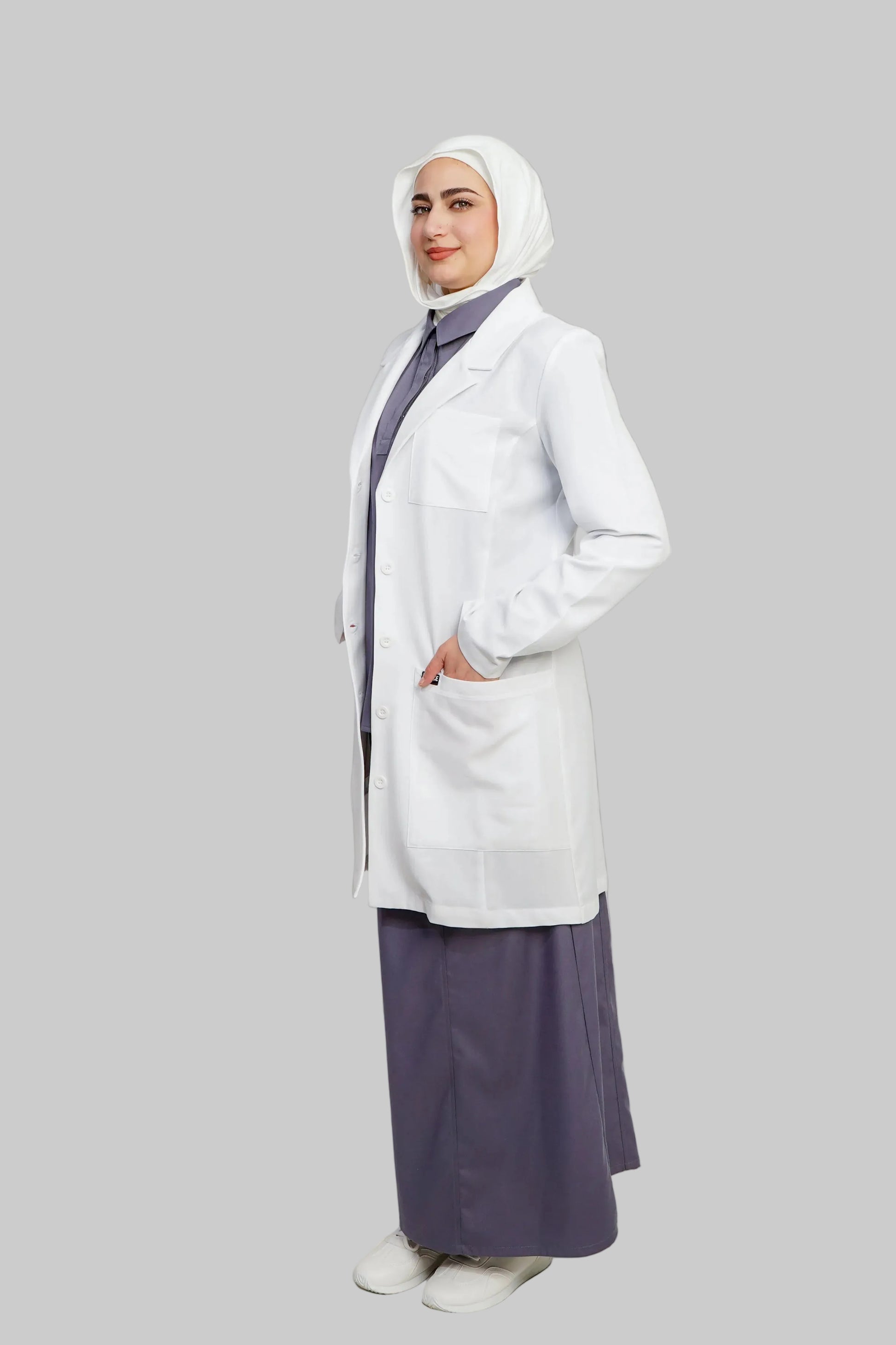 Person wearing a white coat and hijab with a purple skirt on a light gray background
