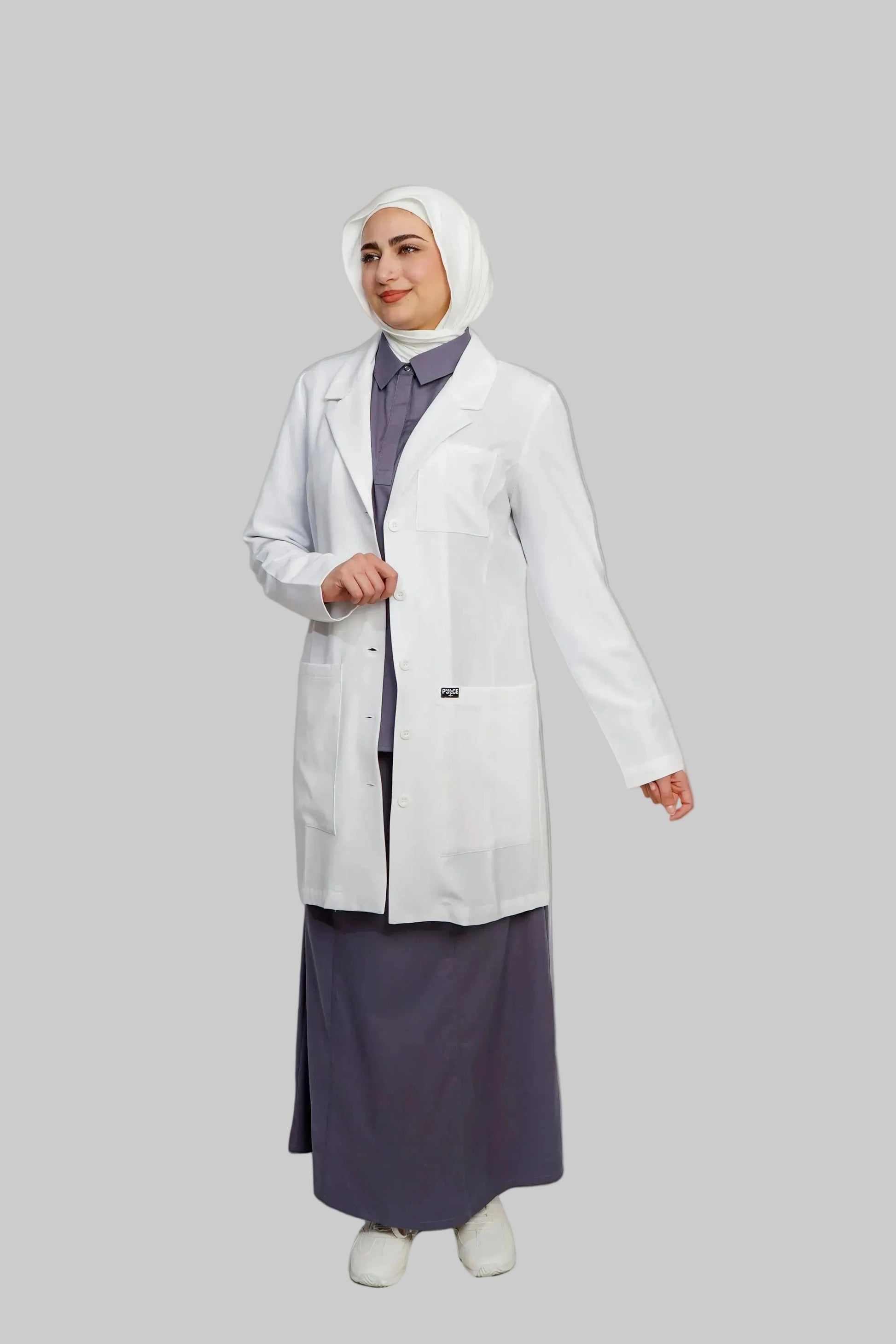 Person wearing a white lab coat over a dark outfit on a plain background