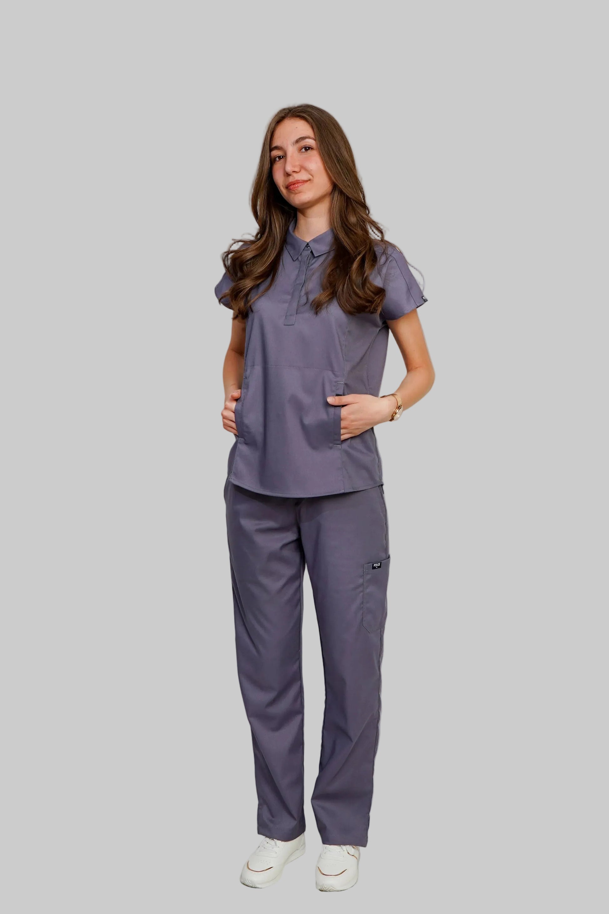 Woman wearing a gray scrub set on a gray background