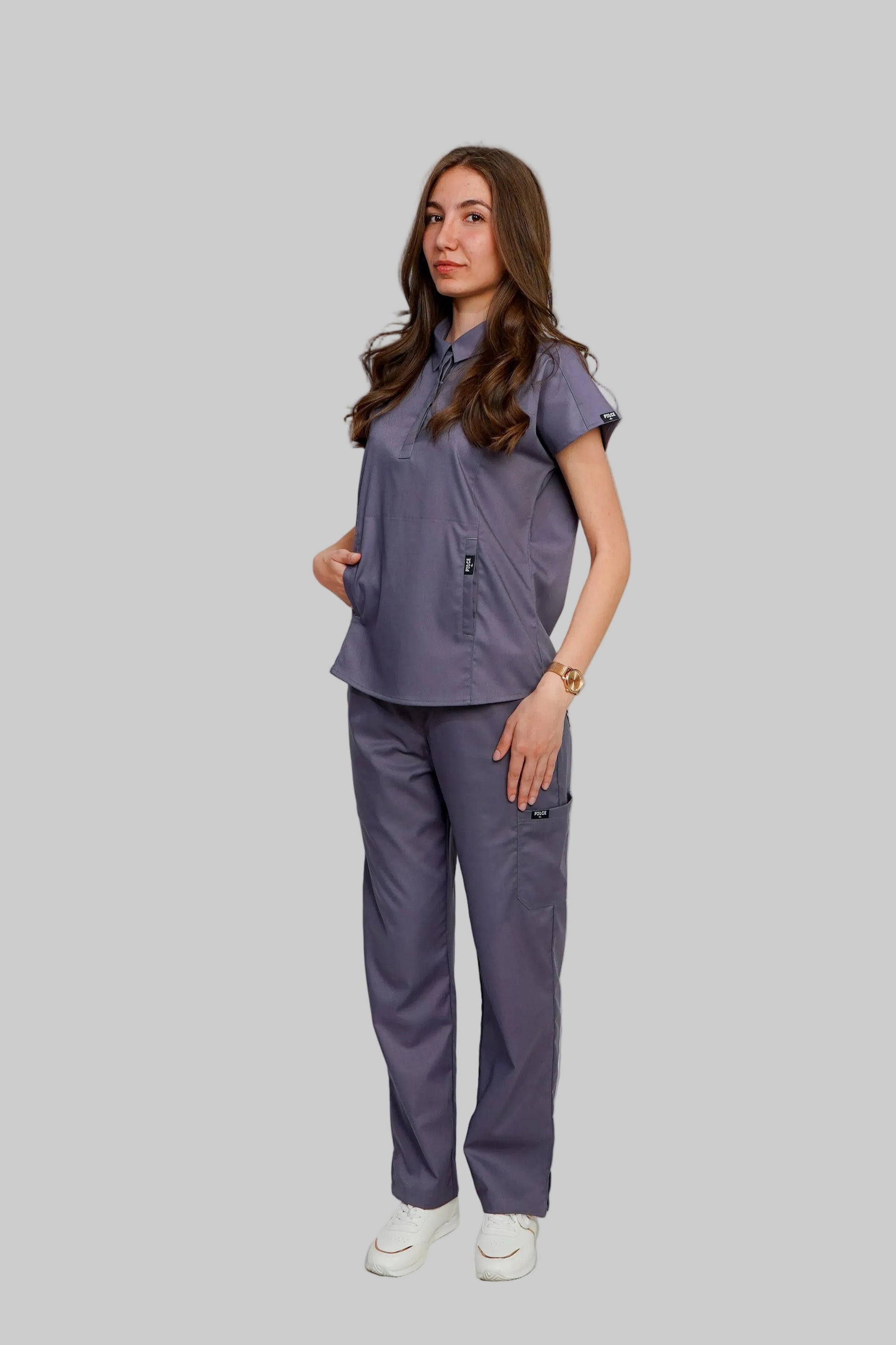 Woman wearing a matching purple scrub set against a white background