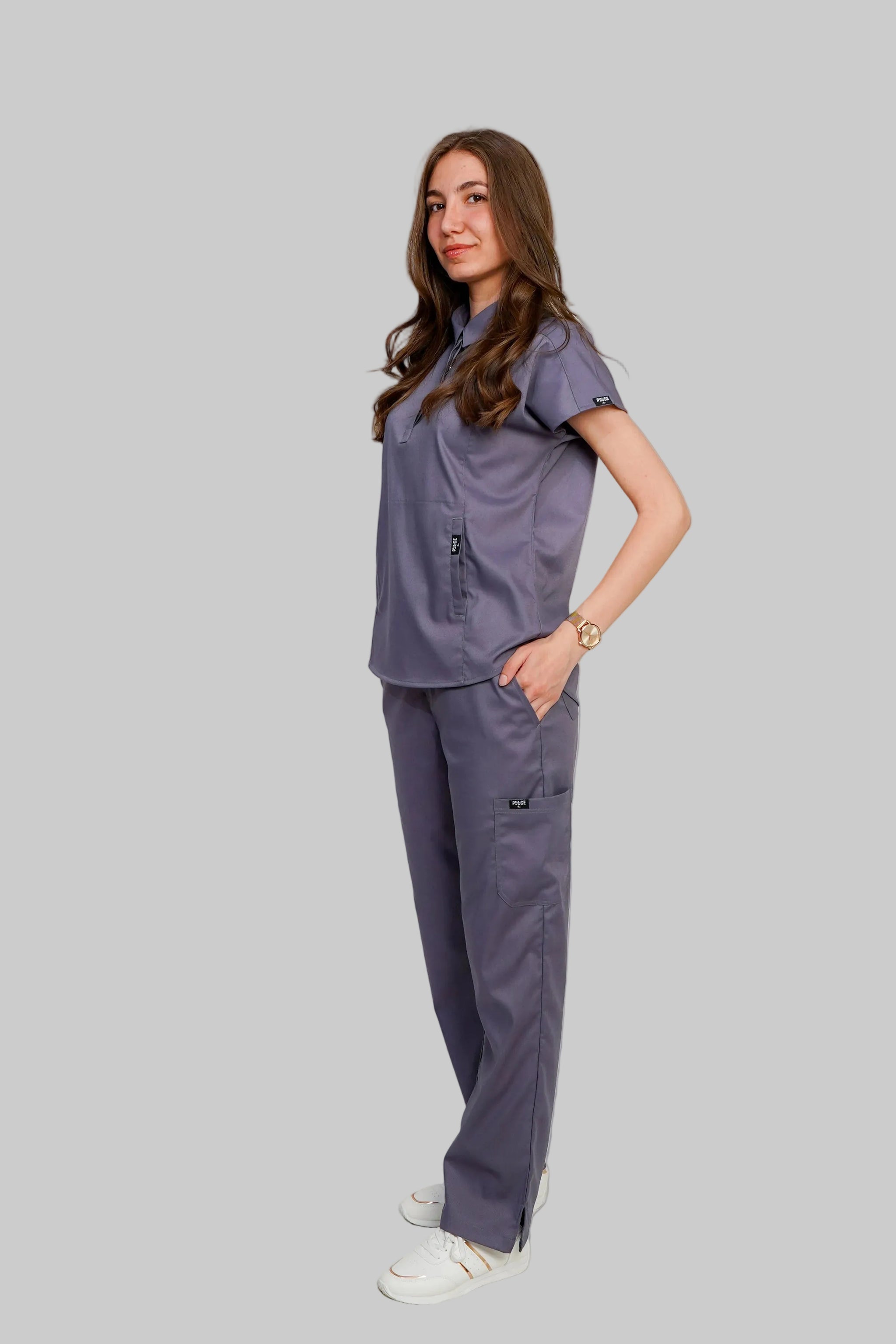 Woman wearing a gray scrub set on a white background