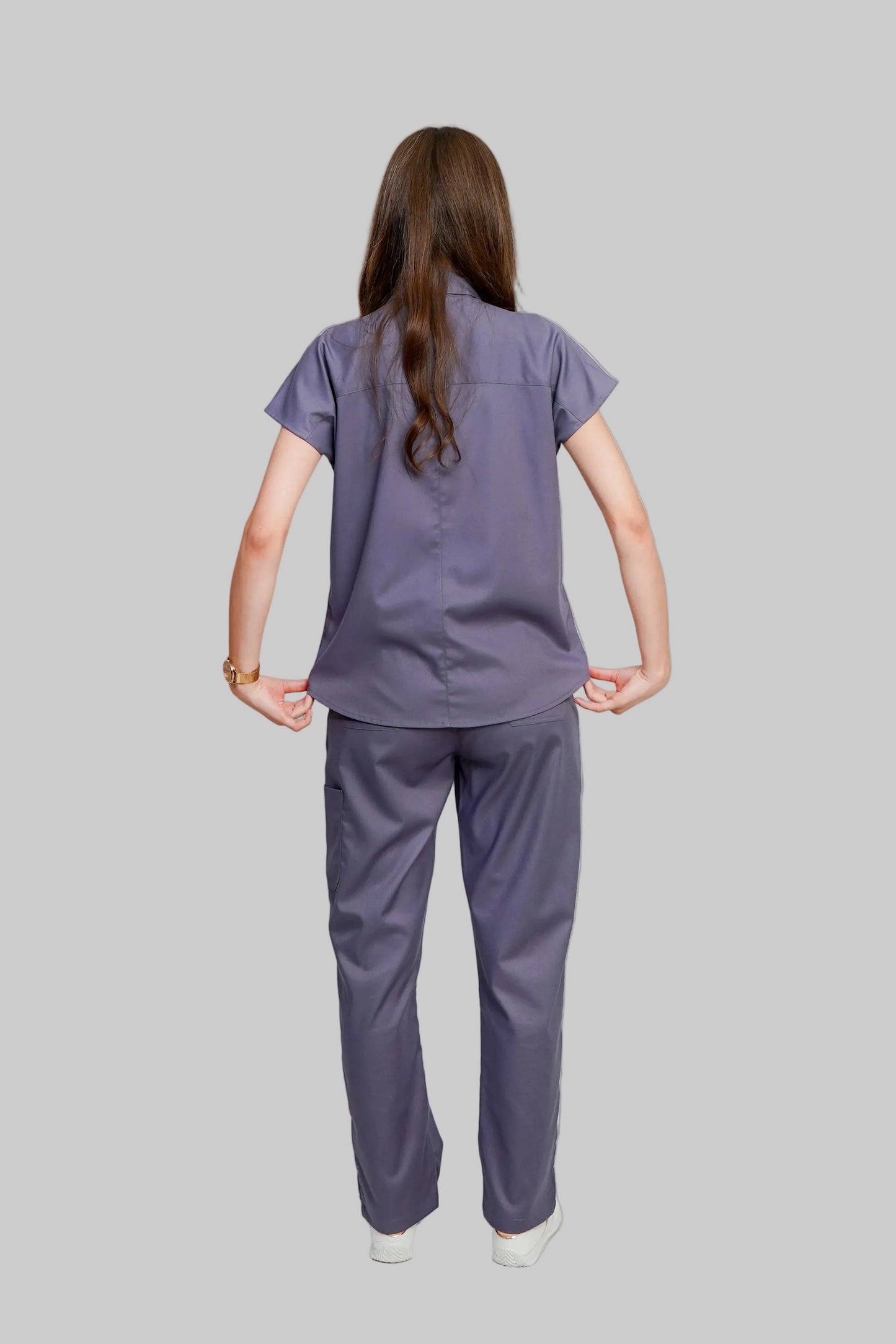 Person wearing a purple scrub set on a white background