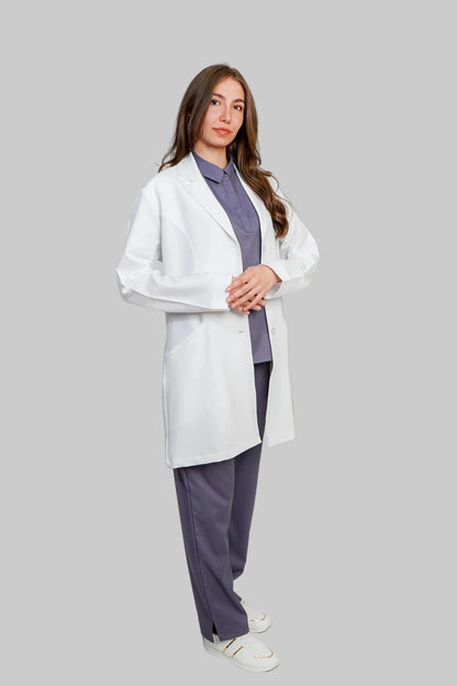 Person wearing a white lab coat over a purple shirt and gray pants on a light gray background