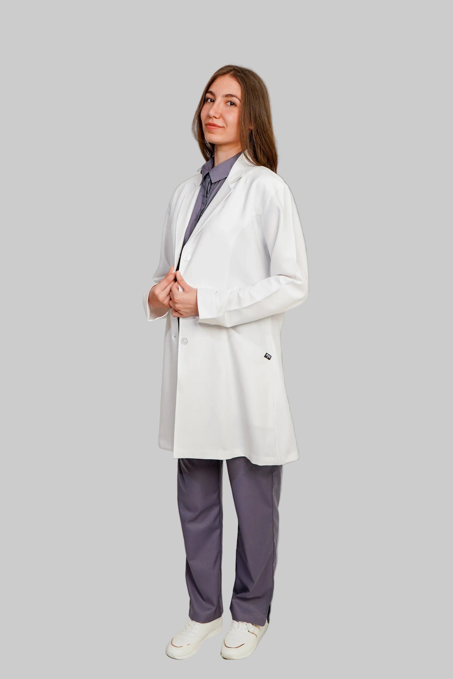 Woman wearing a white blazer over a purple shirt with matching pants on a plain background