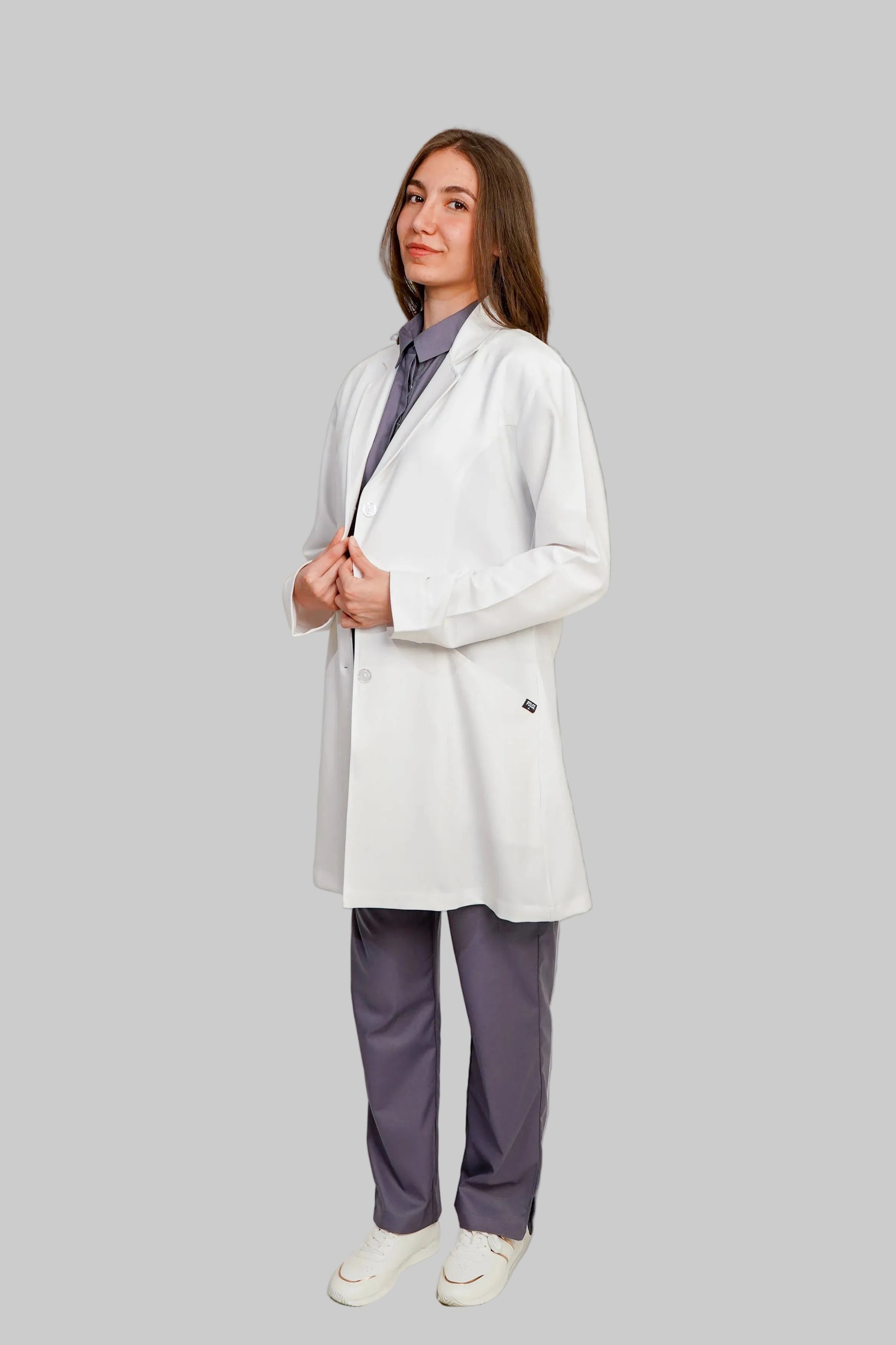 Woman wearing a white blazer over a purple shirt with matching pants on a plain background