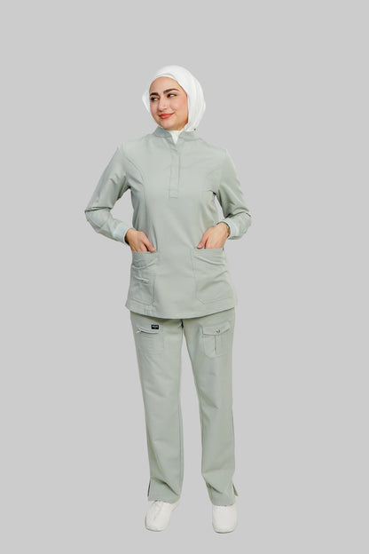 Person wearing a light gray scrub set with a white hijab on a plain background
